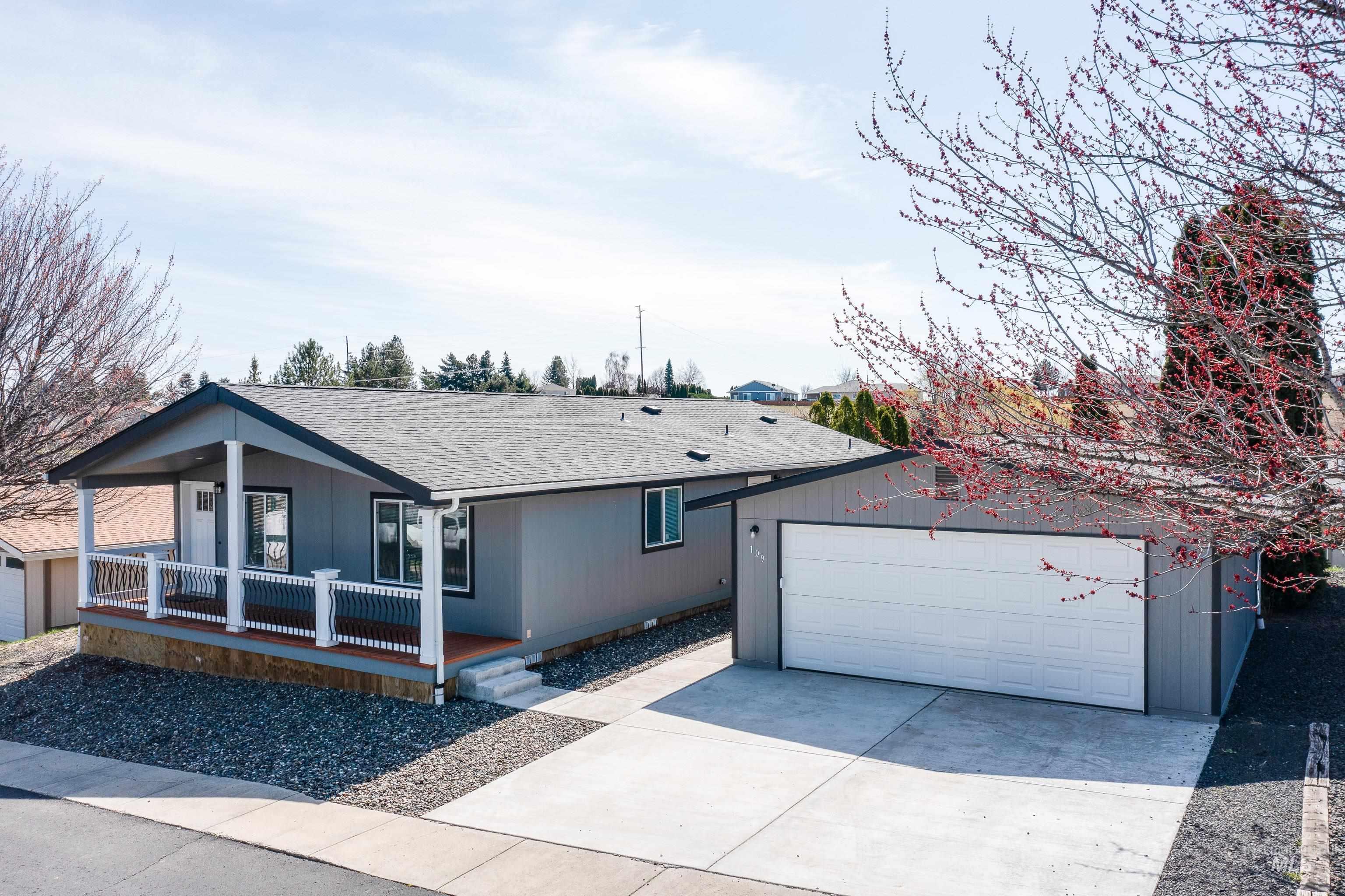 Ranch-style home with an outdoor structure, a shingled roof, covered porch, and a garage