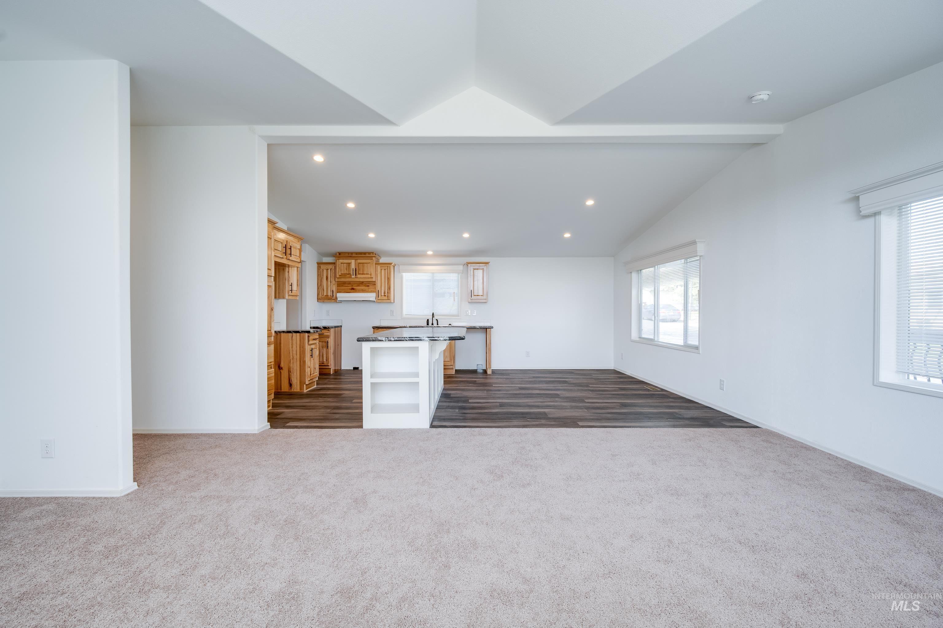 Unfurnished living room featuring recessed lighting, dark carpet, and plenty of natural light