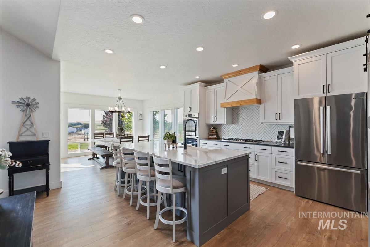 Kitchen with appliances with stainless steel finishes, gray cabinetry, tasteful backsplash, a breakfast bar area, and recessed lighting