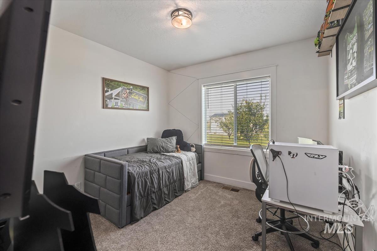 Carpeted bedroom featuring a desk and a textured ceiling