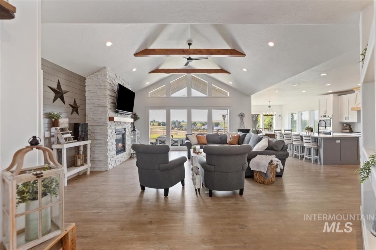 Living area with beam ceiling, light wood-style flooring, a fireplace, high vaulted ceiling, and recessed lighting