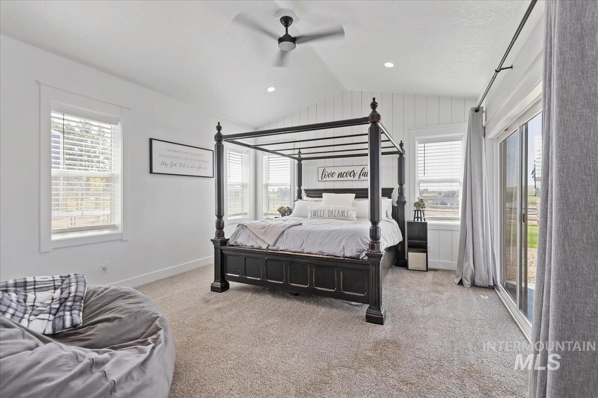 Bedroom featuring light colored carpet, vaulted ceiling, access to exterior, a ceiling fan, and recessed lighting