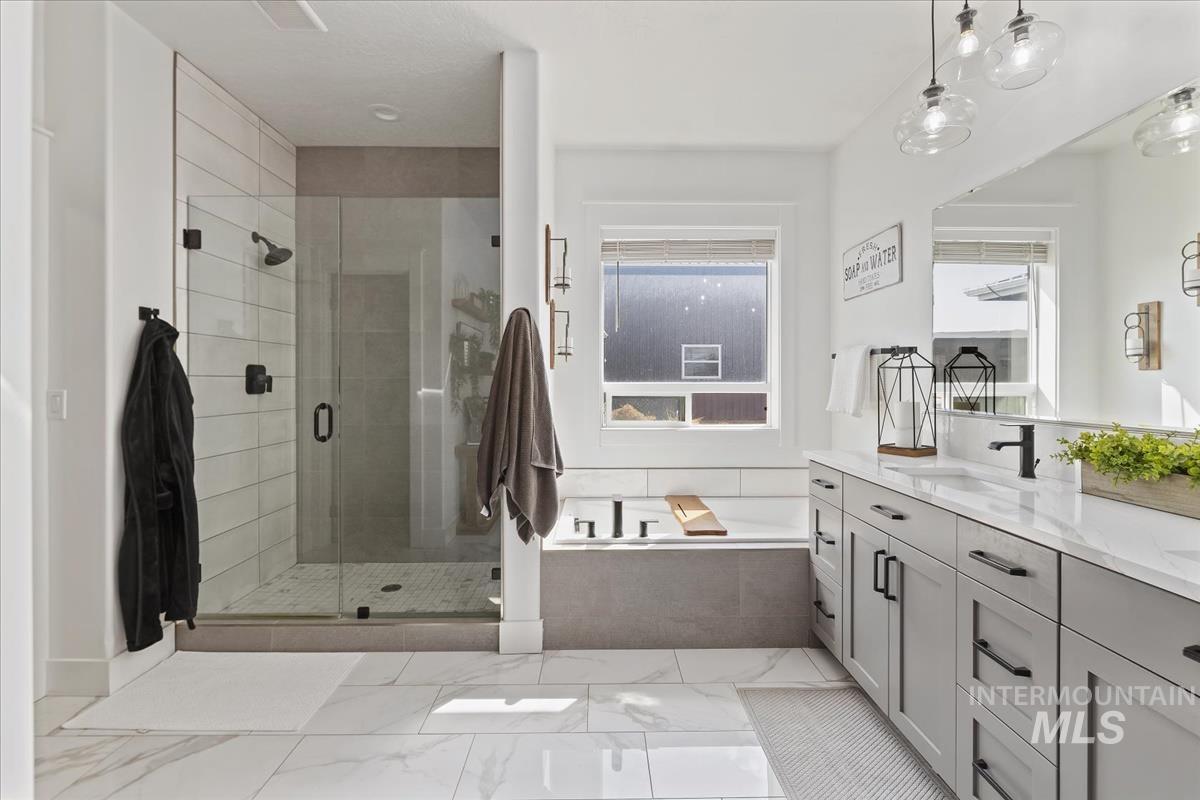 Bathroom with double vanity, a bath, a shower stall, and light marble finish floors