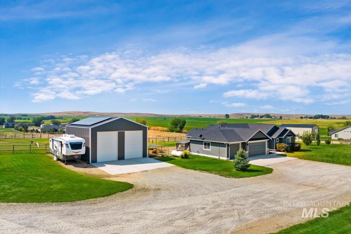 View of front facade with a view of rural / pastoral area, a detached garage, driveway, and an outdoor structure