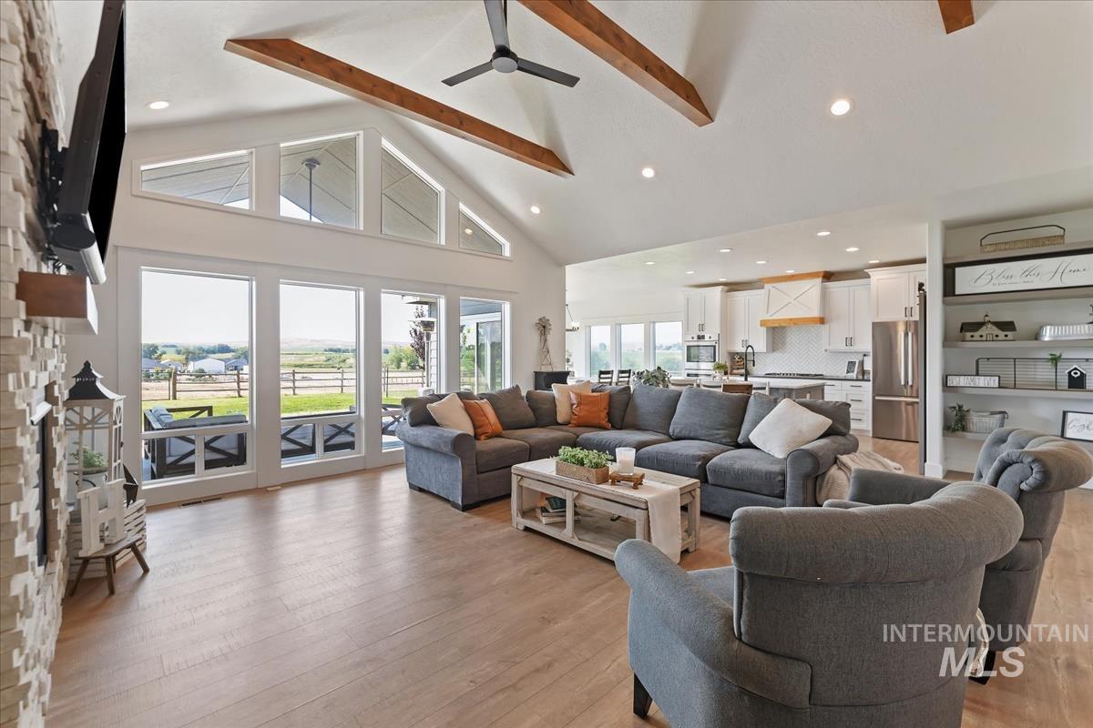 Living room featuring high vaulted ceiling, beam ceiling, light wood-style flooring, recessed lighting, and a fireplace