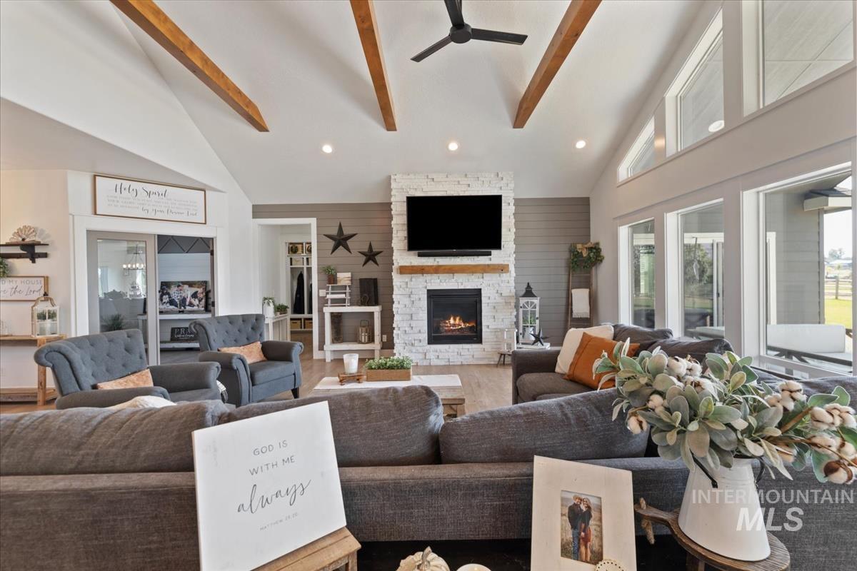 Living area featuring high vaulted ceiling, beam ceiling, a fireplace, recessed lighting, and wood finished floors