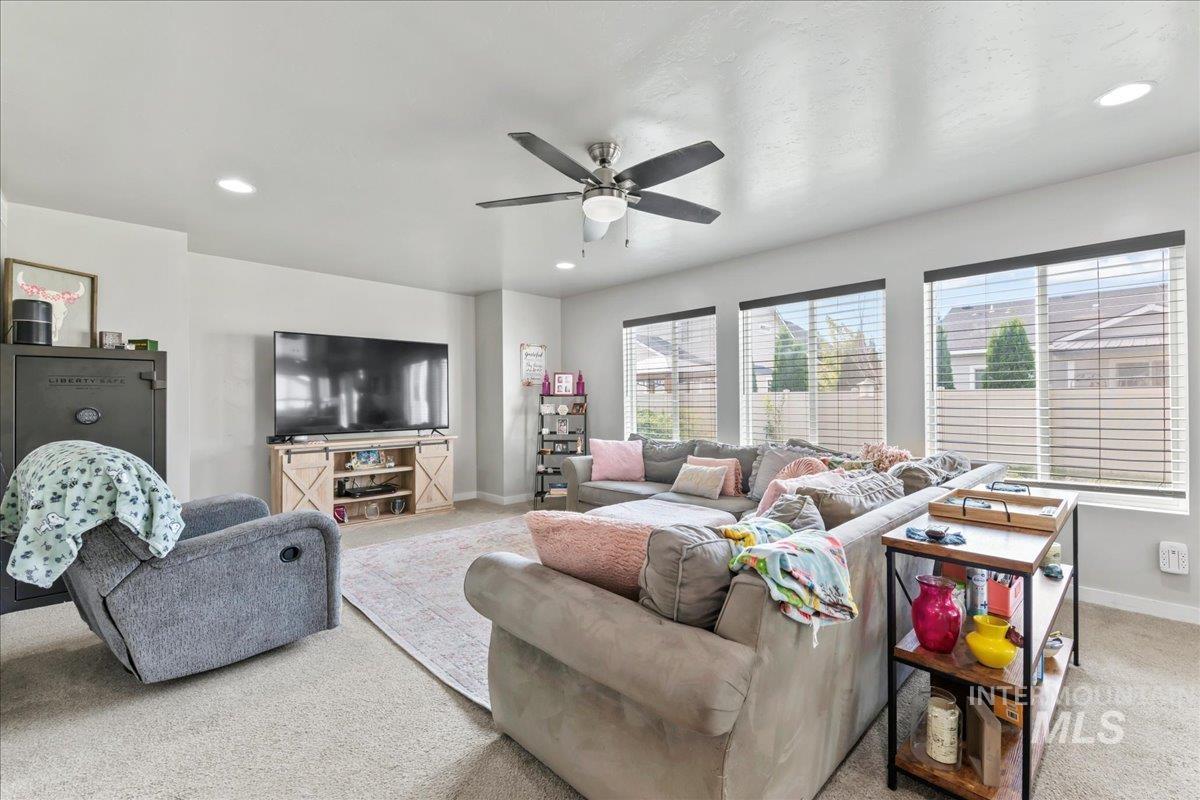 Living room with light colored carpet, recessed lighting, and ceiling fan