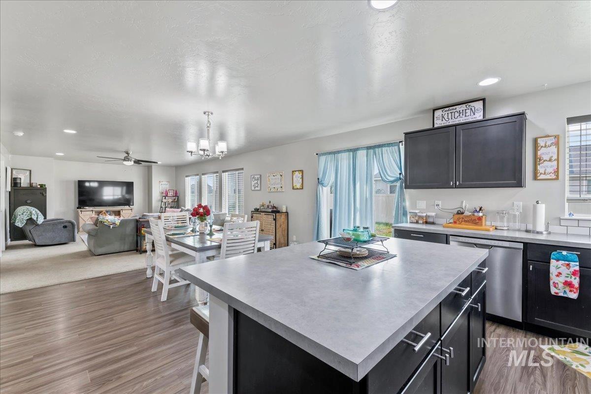 Kitchen with dark cabinetry, recessed lighting, a center island, light countertops, and open floor plan
