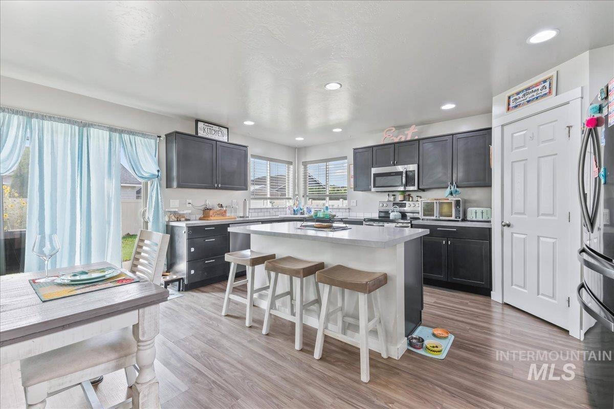 Kitchen featuring a breakfast bar area, light wood-type flooring, appliances with stainless steel finishes, recessed lighting, and a center island