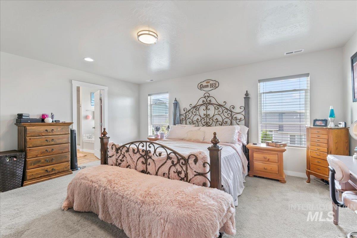 Bedroom featuring light carpet and ensuite bathroom