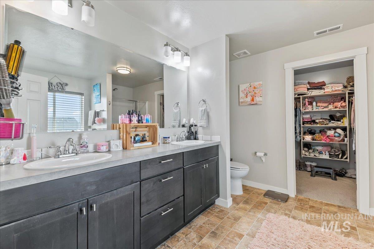 Bathroom with a stall shower, double vanity, and a spacious closet