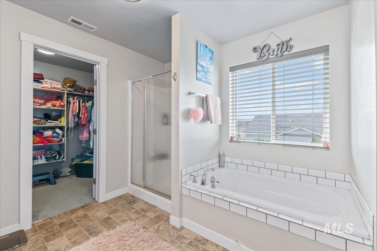 Full bathroom with a stall shower, a garden tub, and a spacious closet