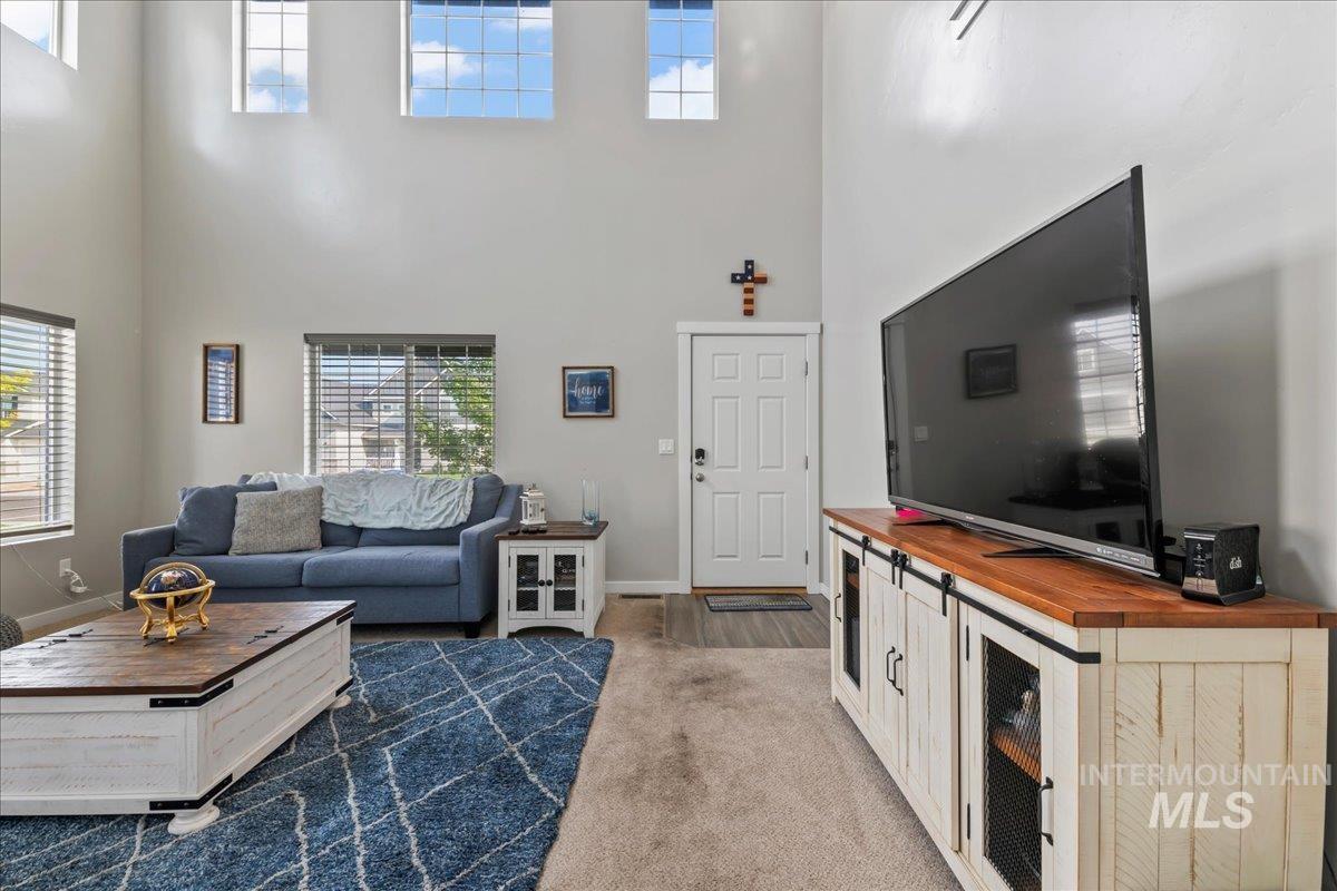 Living room featuring plenty of natural light, a high ceiling, and dark carpet
