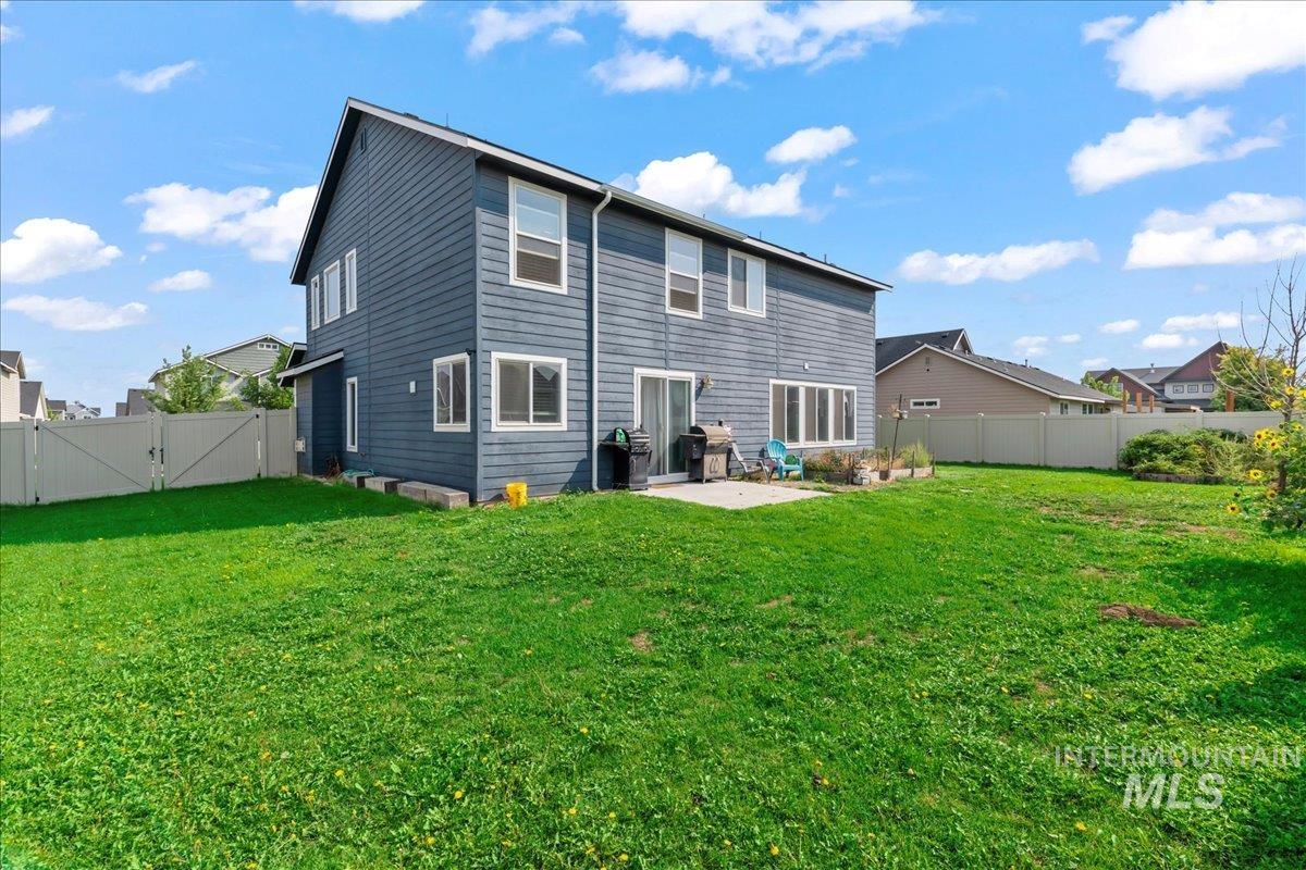 Rear view of property with a patio area, a fenced backyard, and a gate