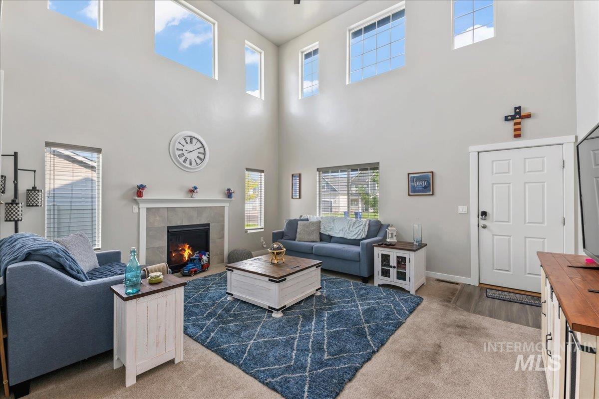 Carpeted living area with a tiled fireplace and a towering ceiling