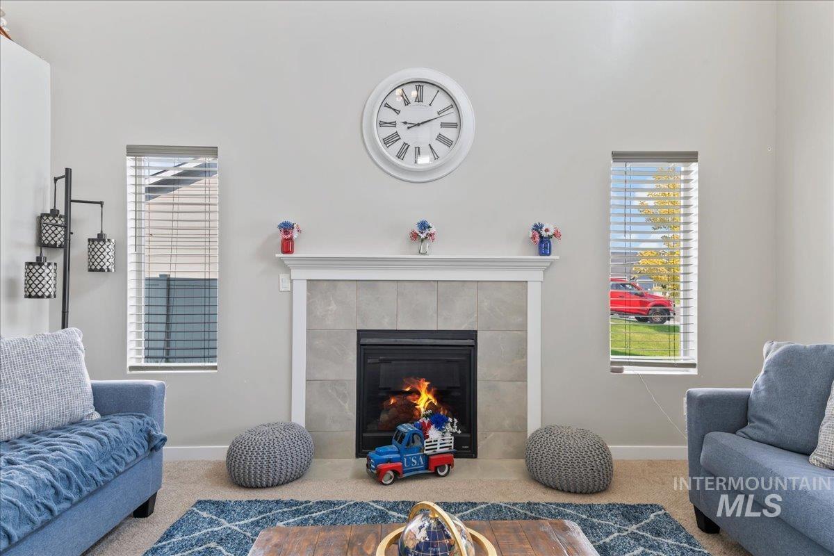 Carpeted living area featuring a tile fireplace and healthy amount of natural light