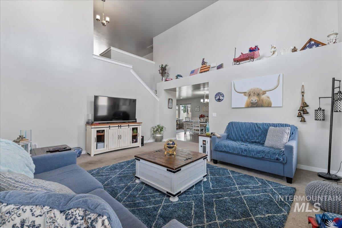 Carpeted living area featuring a chandelier and a high ceiling