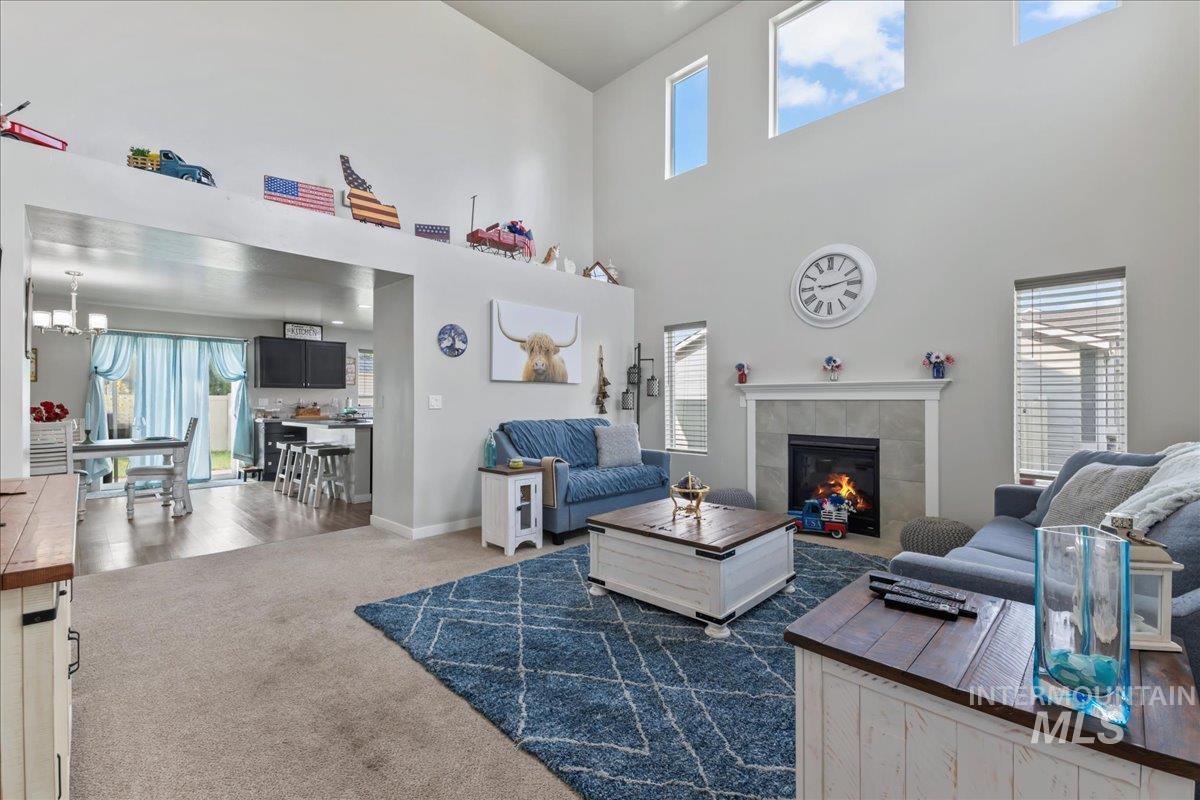 Carpeted living area featuring healthy amount of natural light, a tile fireplace, and a towering ceiling