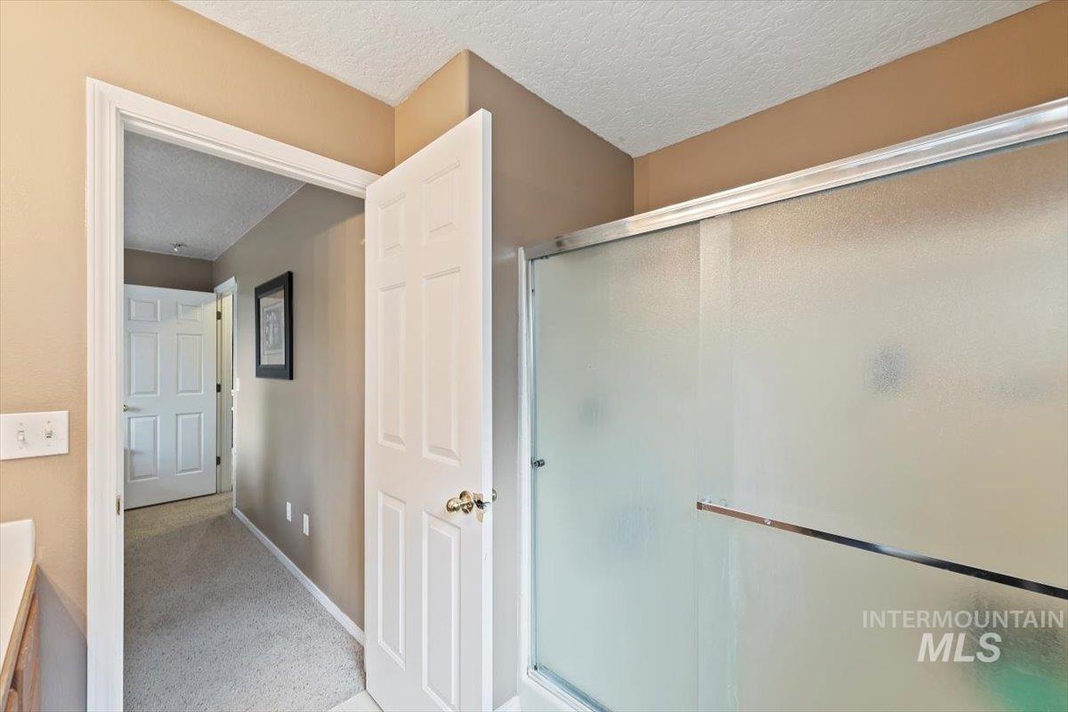 Full bath with a textured ceiling, a stall shower, and vanity