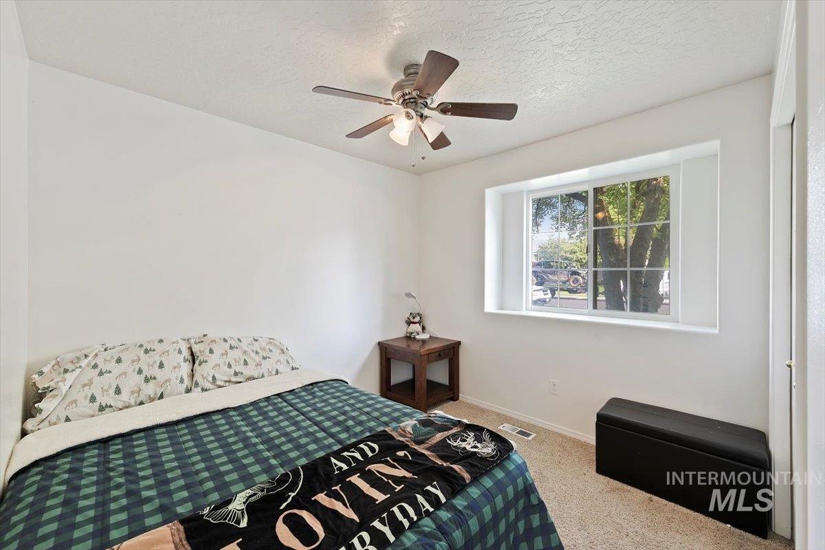 Carpeted bedroom with a textured ceiling and ceiling fan