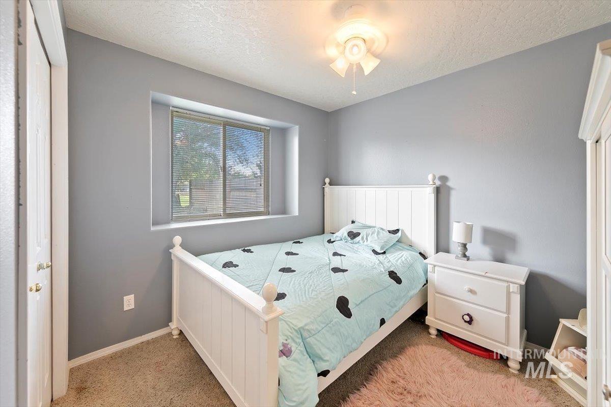 Carpeted bedroom with a textured ceiling and baseboards