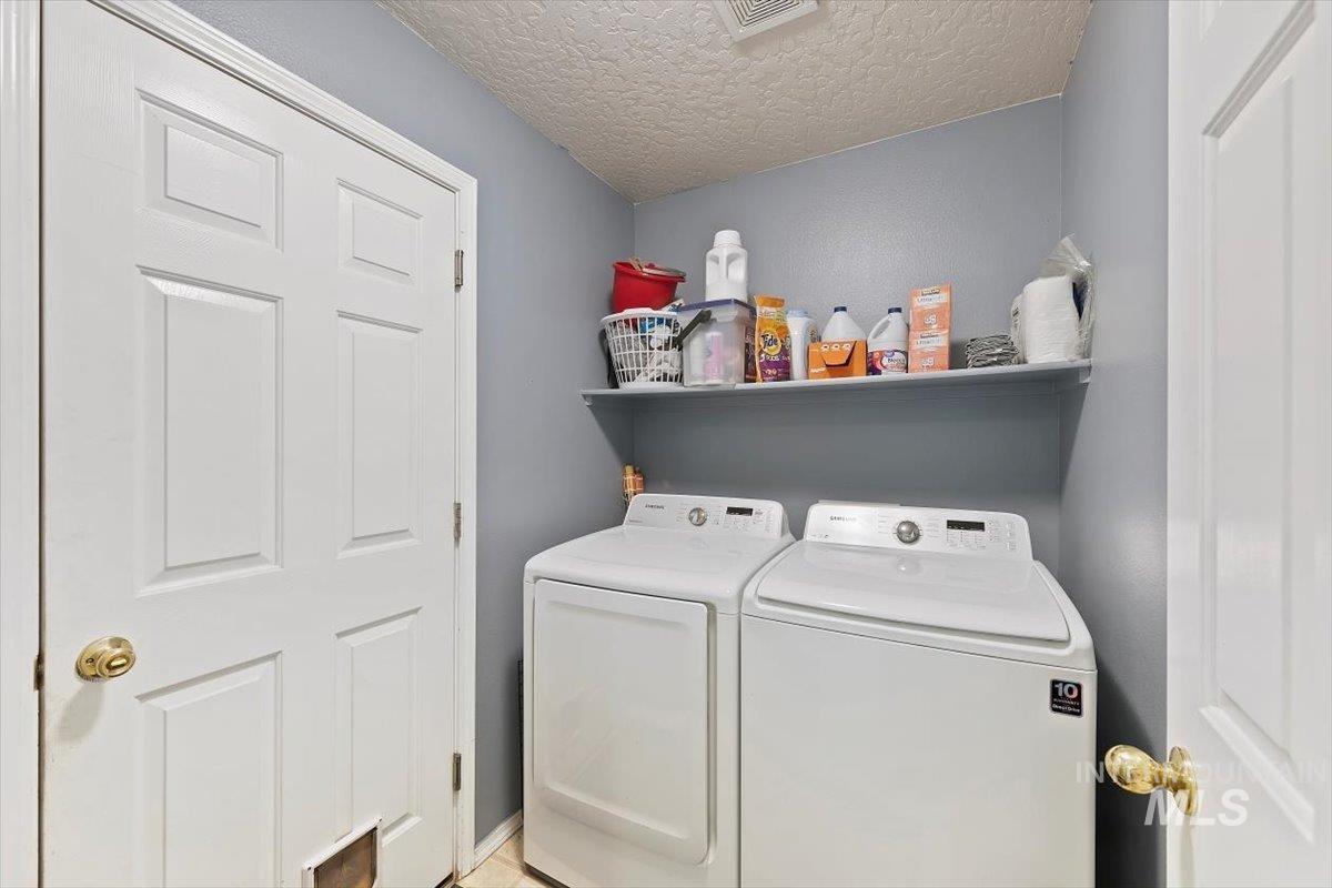 Washroom featuring washer and dryer and a textured ceiling