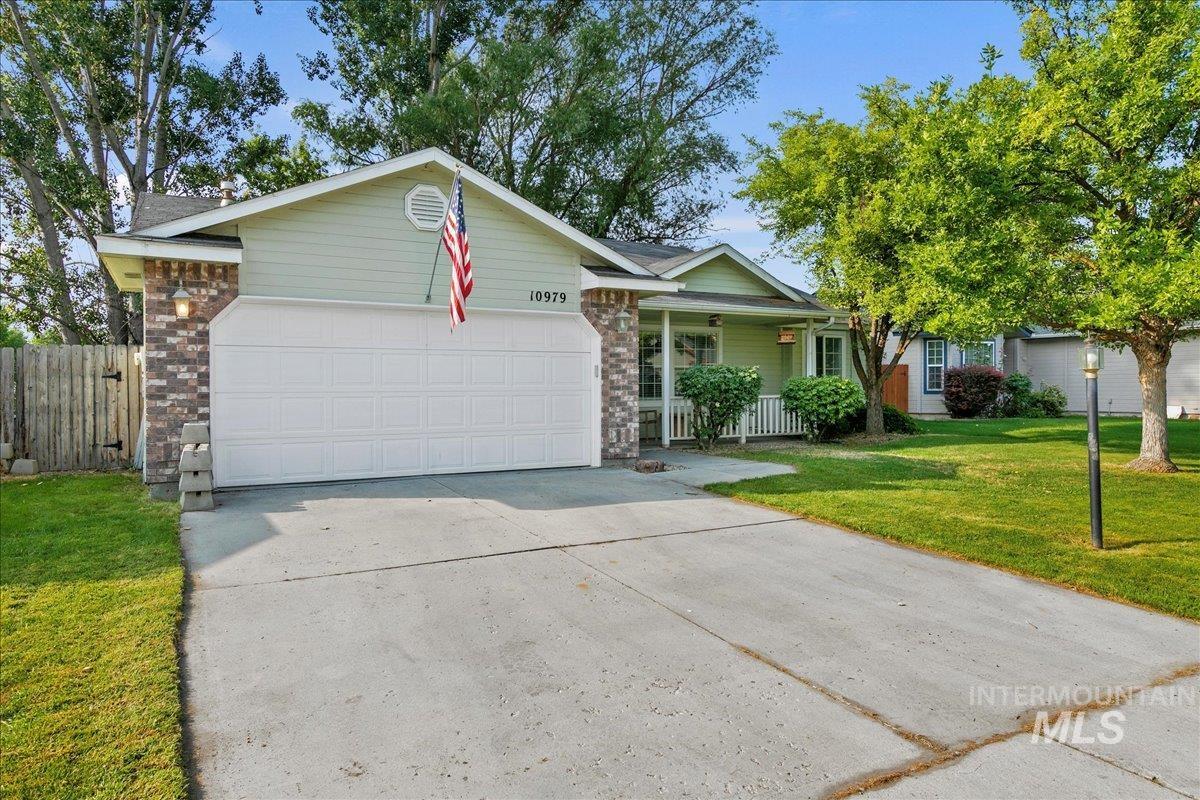 Ranch-style home with driveway, an attached garage, a porch, and stone siding