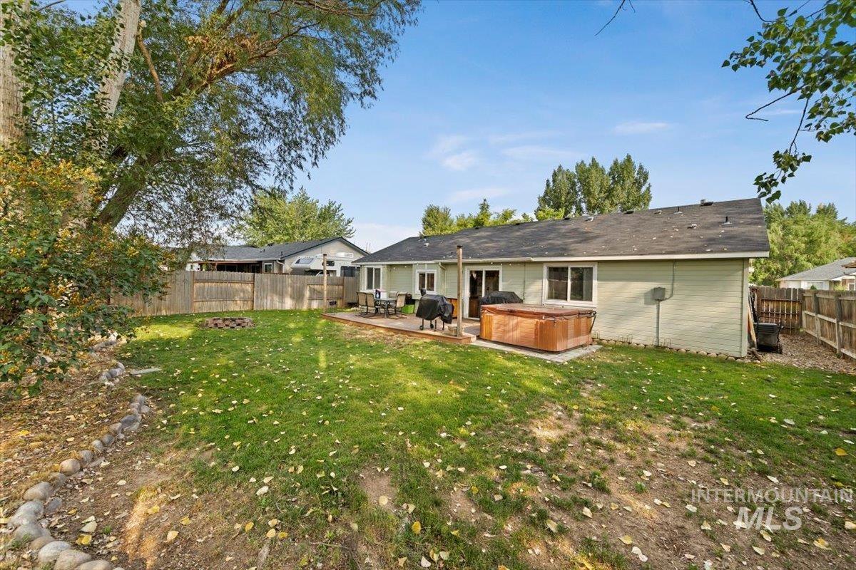 Rear view of house with a hot tub, a deck, and a fenced backyard