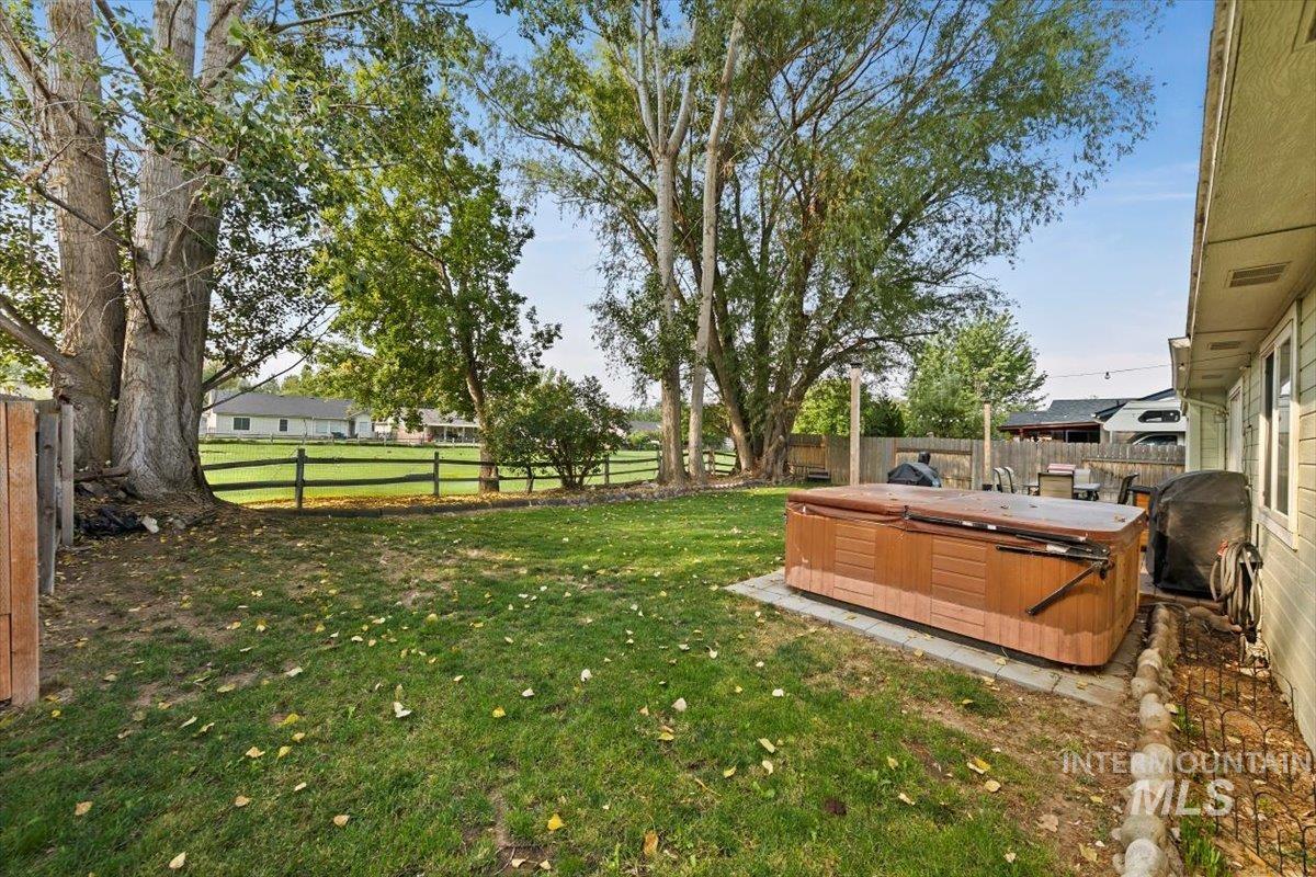 Fenced backyard featuring a hot tub