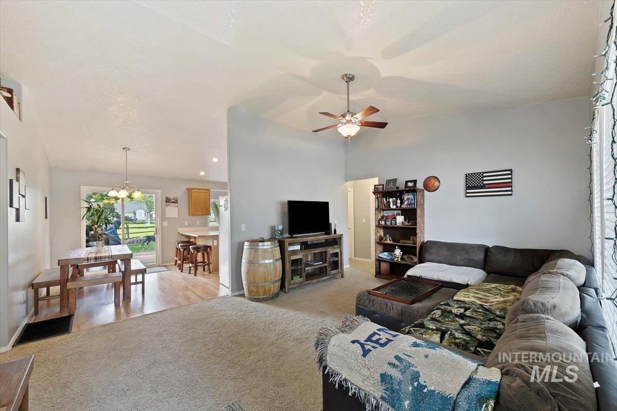 Living area featuring lofted ceiling, carpet floors, a textured ceiling, and ceiling fan