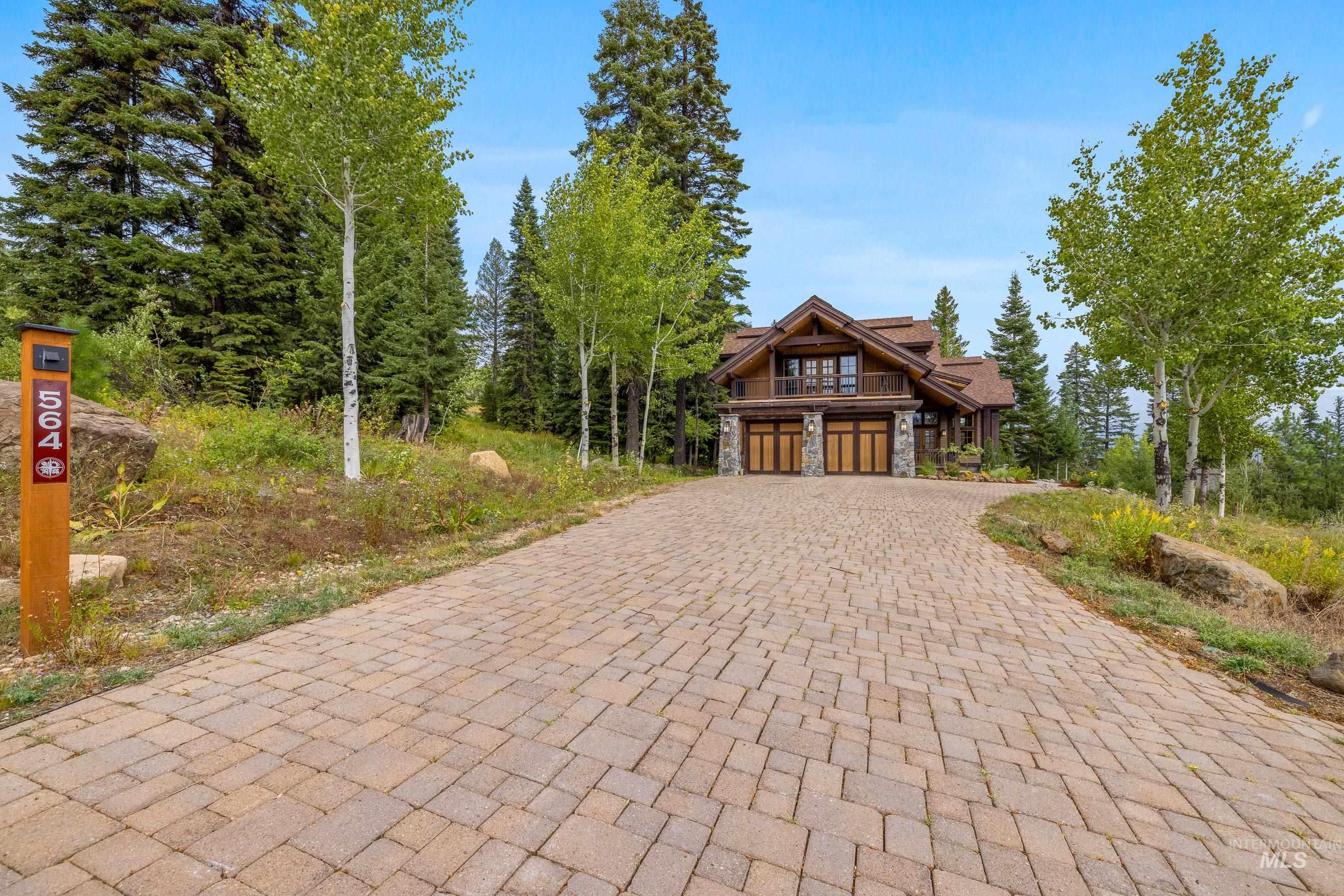 View of front of home with stone siding, decorative driveway, and a garage