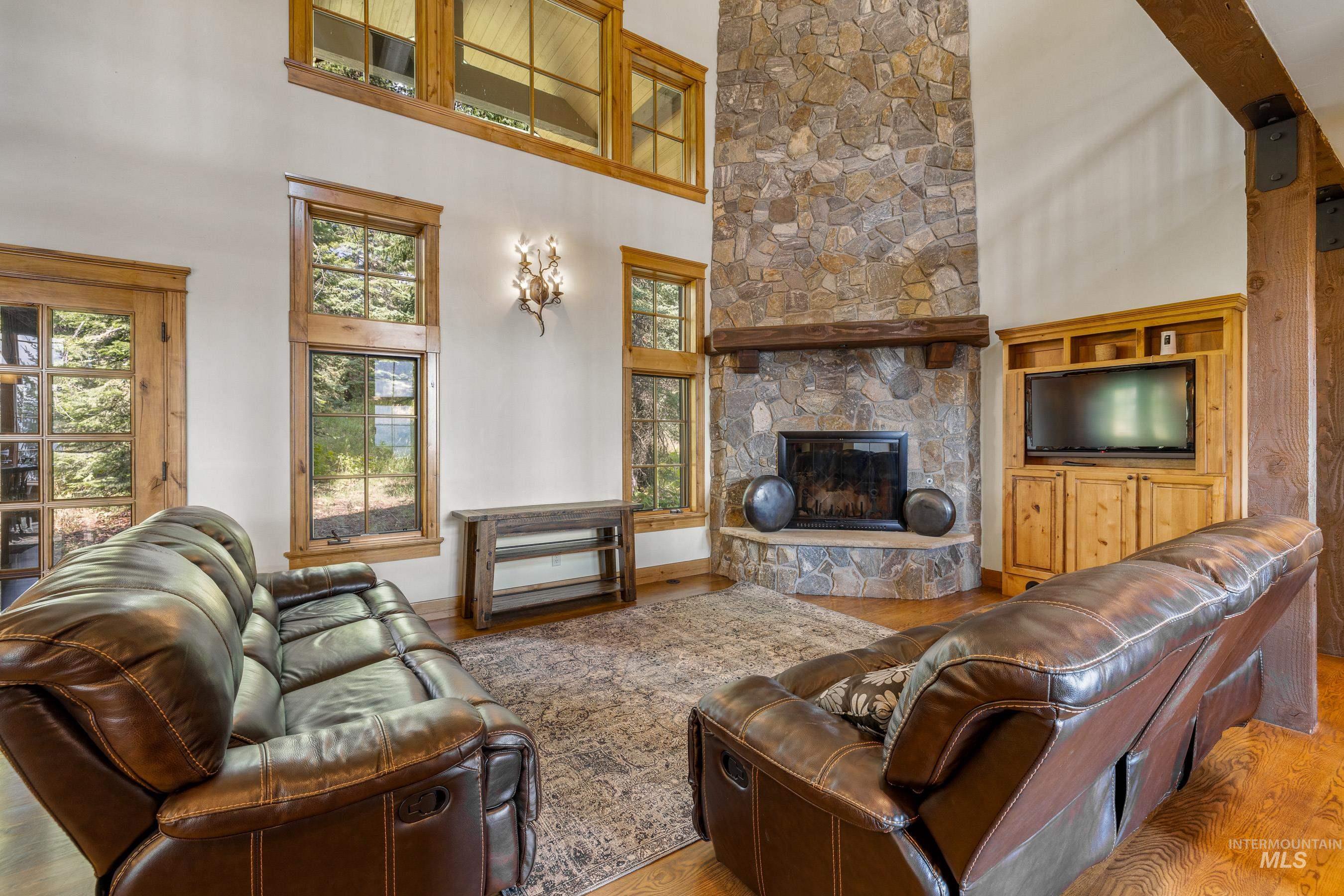 Living area with a fireplace, wood finished floors, a towering ceiling, and plenty of natural light