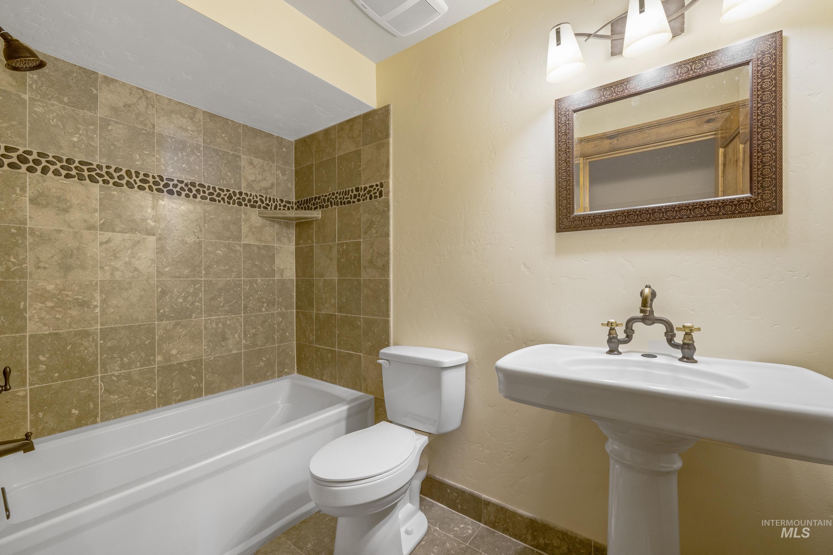Bathroom with a textured wall, bathing tub / shower combination, and tile patterned floors