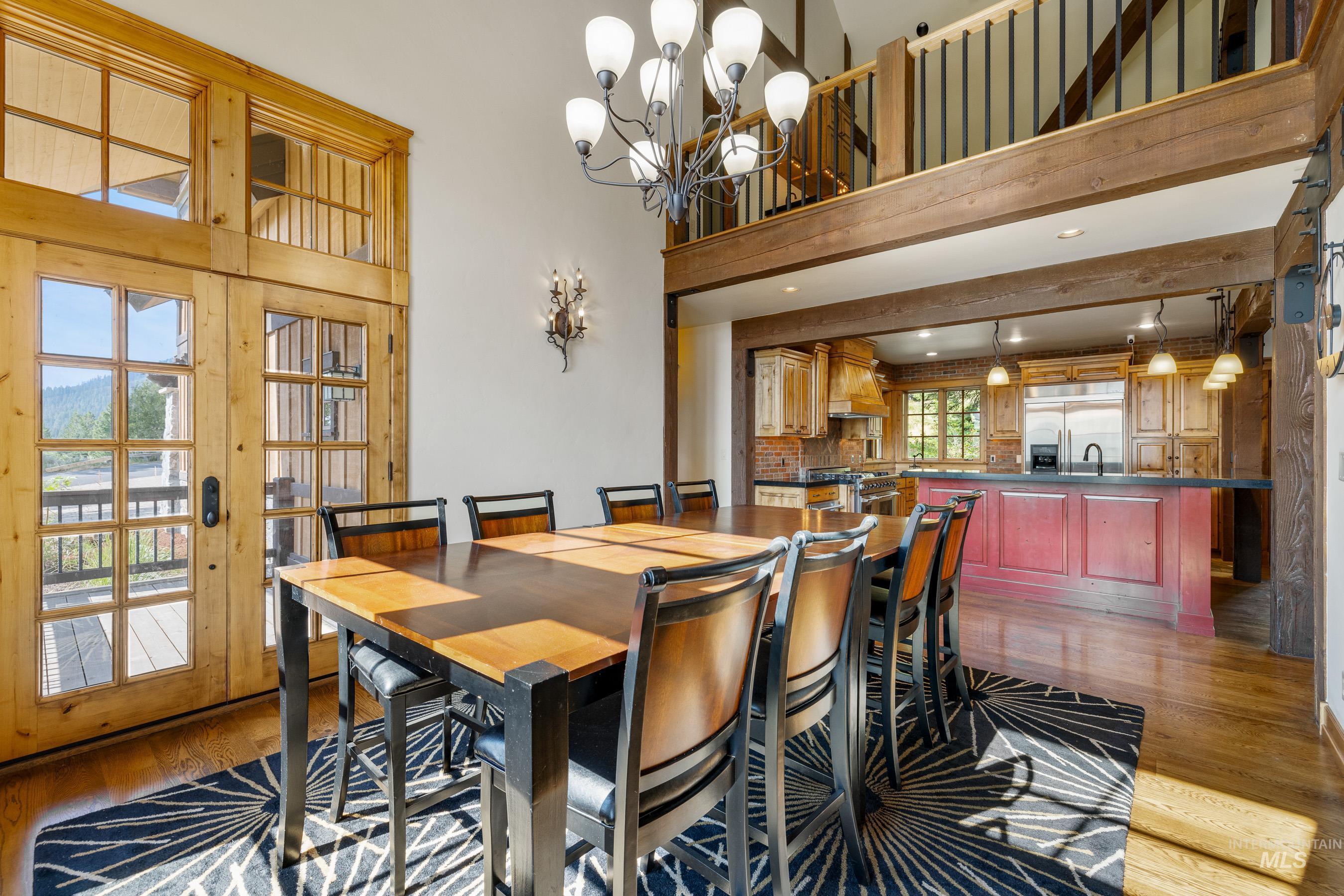 Dining space featuring light wood-style floors, a chandelier, and a towering ceiling