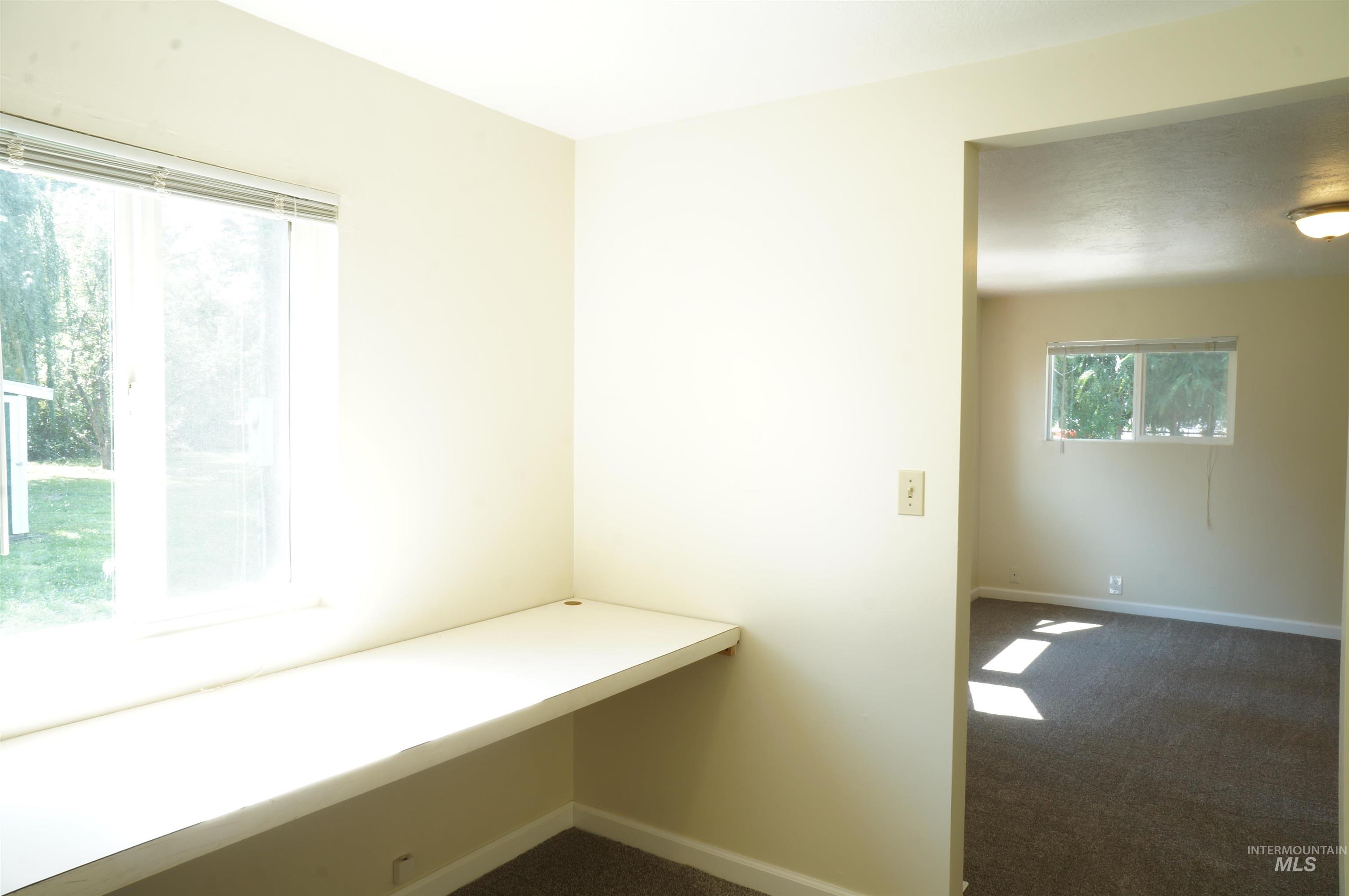 Unfurnished office featuring dark carpet and baseboards
