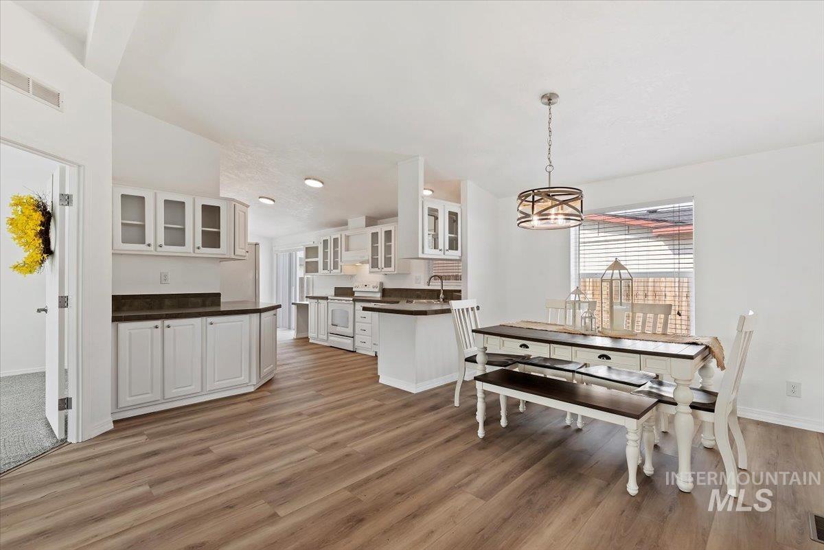 Dining room featuring light wood-style floors, a chandelier, and lofted ceiling