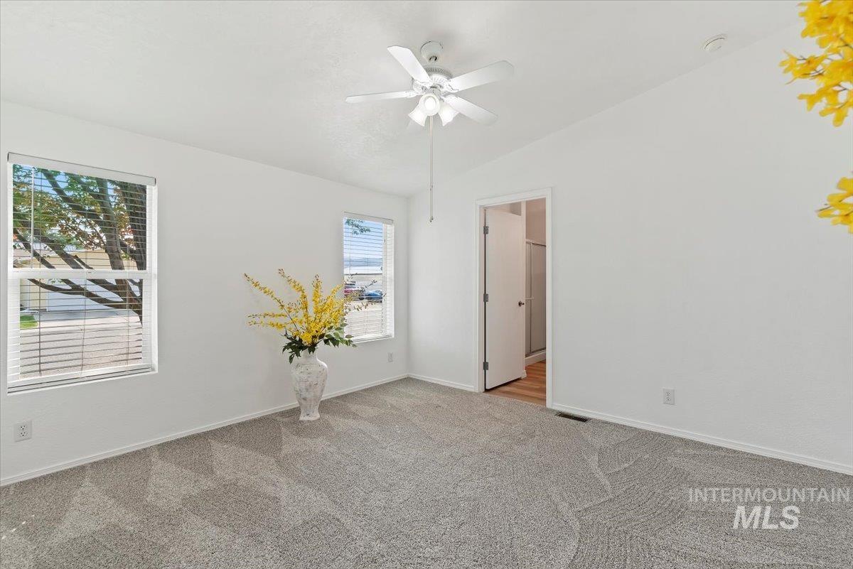 Empty room with lofted ceiling, a ceiling fan, and carpet flooring