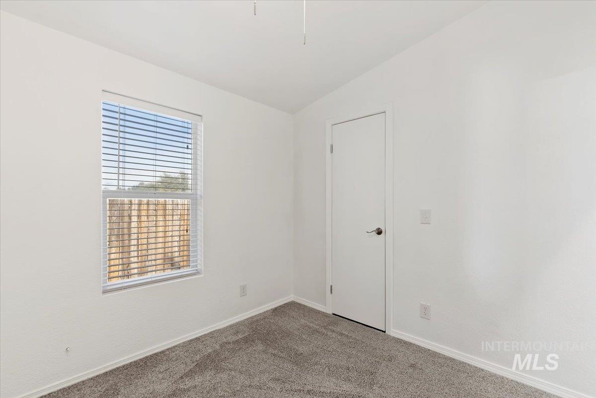 Carpeted empty room with lofted ceiling and baseboards