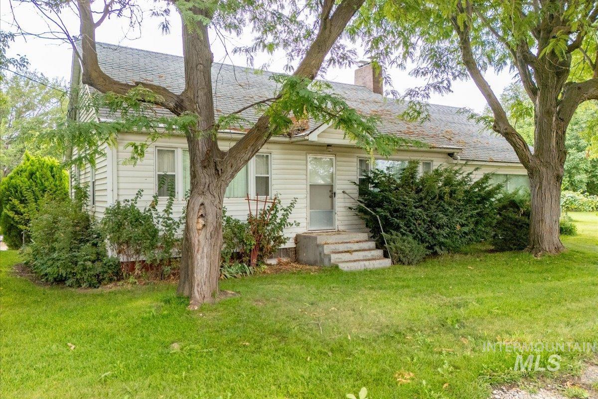 View of front of house with a front yard, a chimney, and roof with shingles