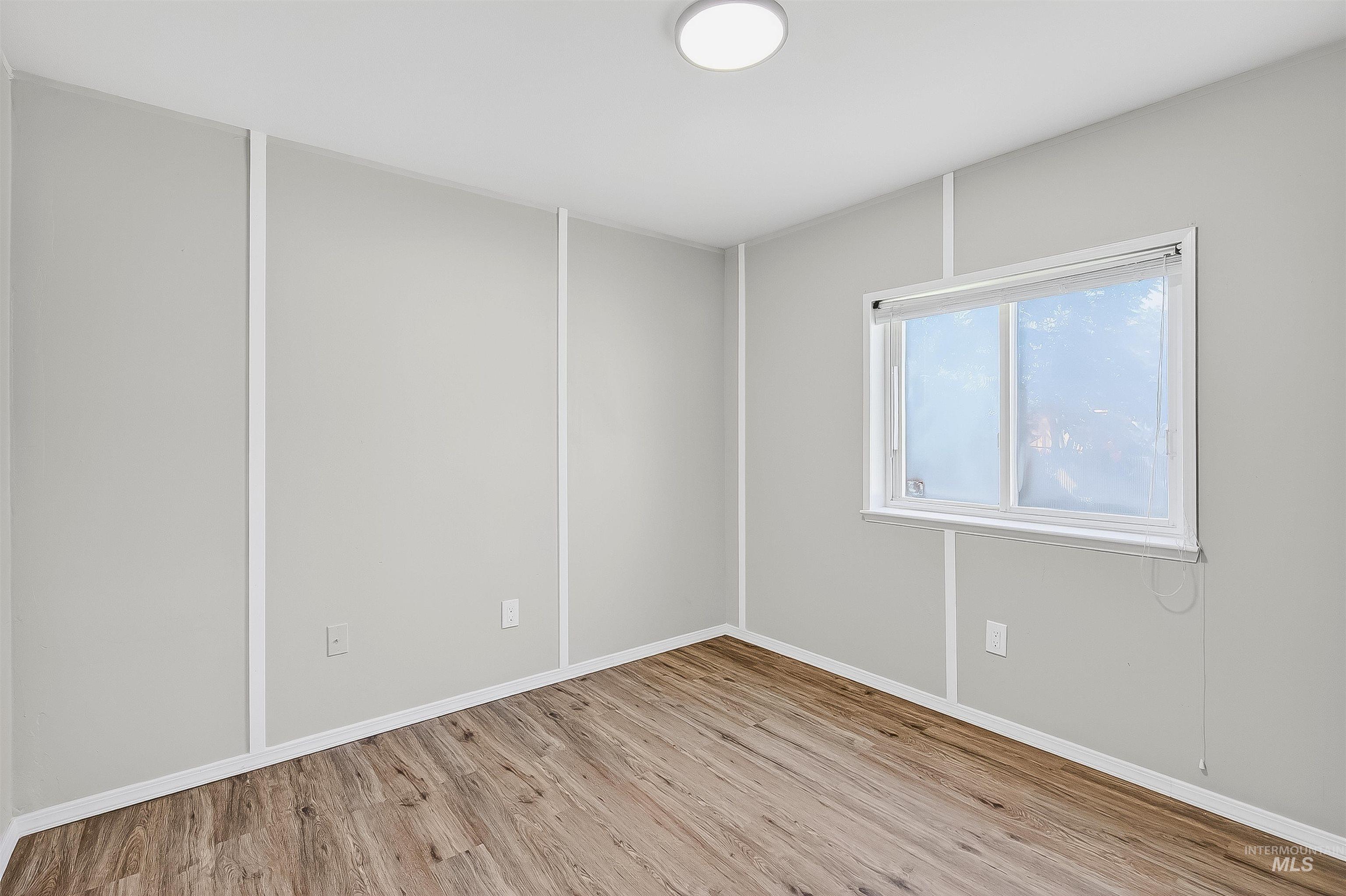 Unfurnished room with light wood finished floors and baseboards