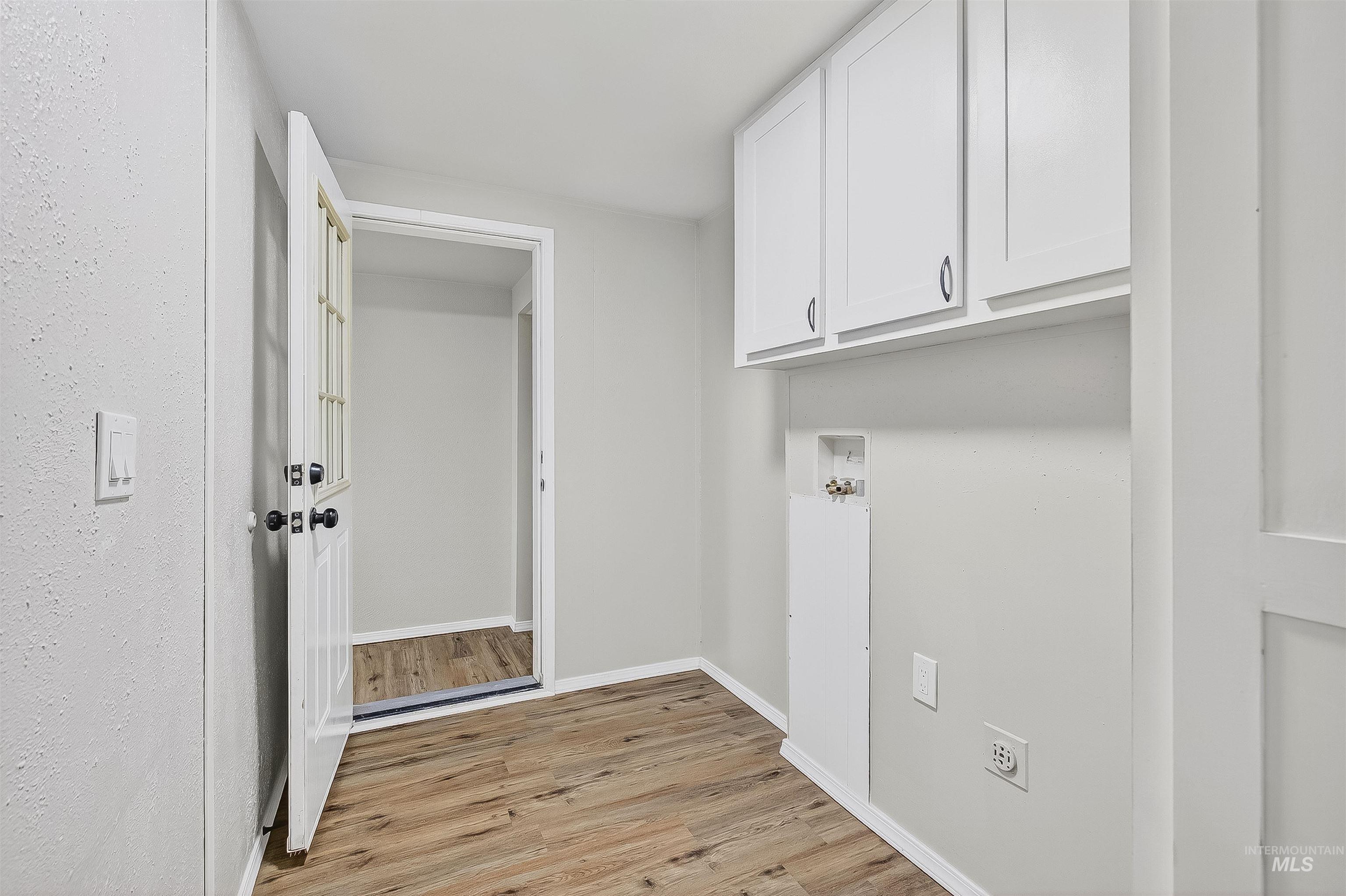 Laundry area featuring light wood-type flooring, hookup for a washing machine, and cabinet space