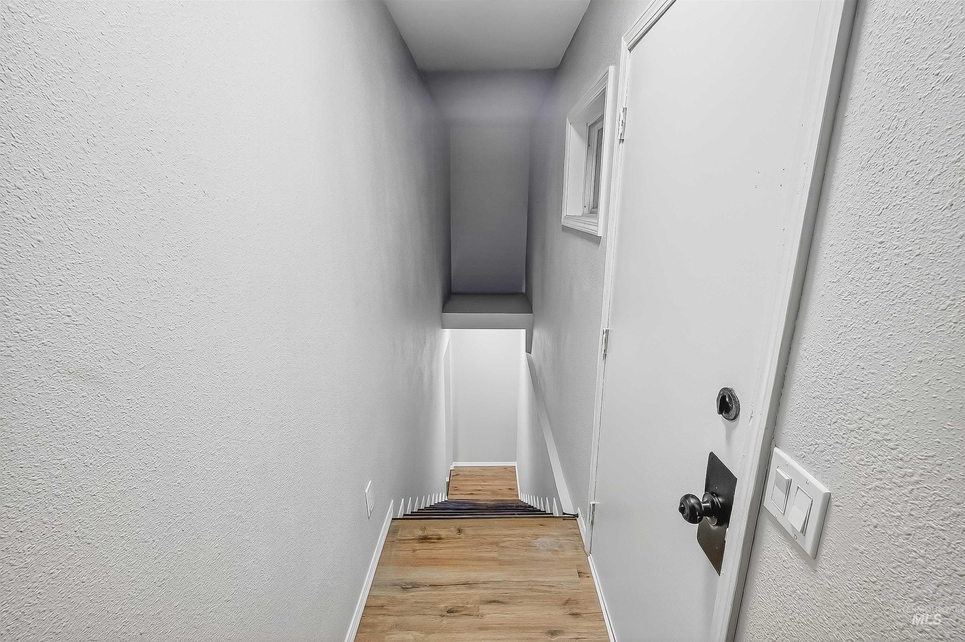 Staircase featuring wood finished floors and a textured wall
