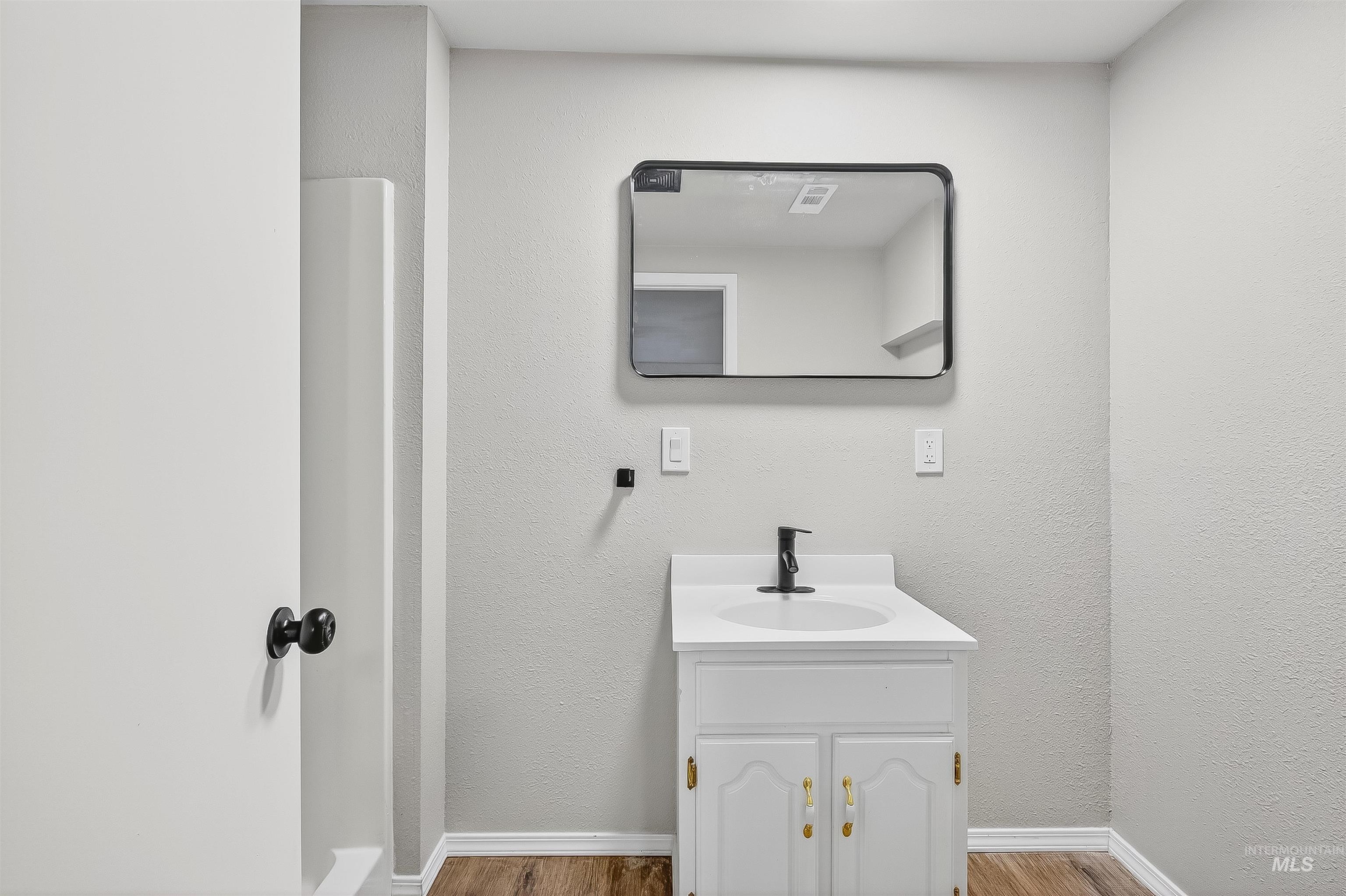 Bathroom with vanity, wood finished floors, and a textured wall