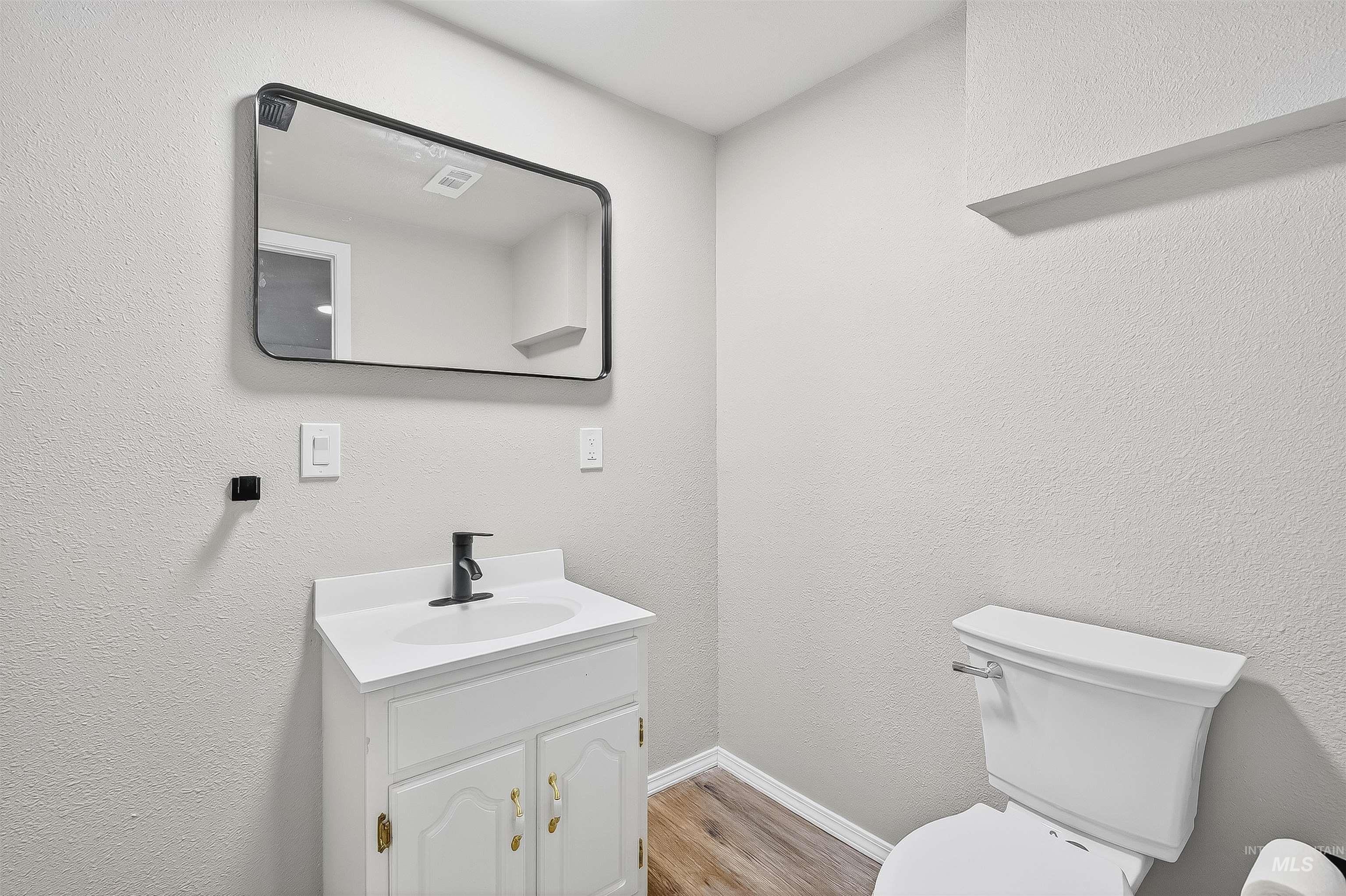 Bathroom with a textured wall, vanity, and light wood-type flooring