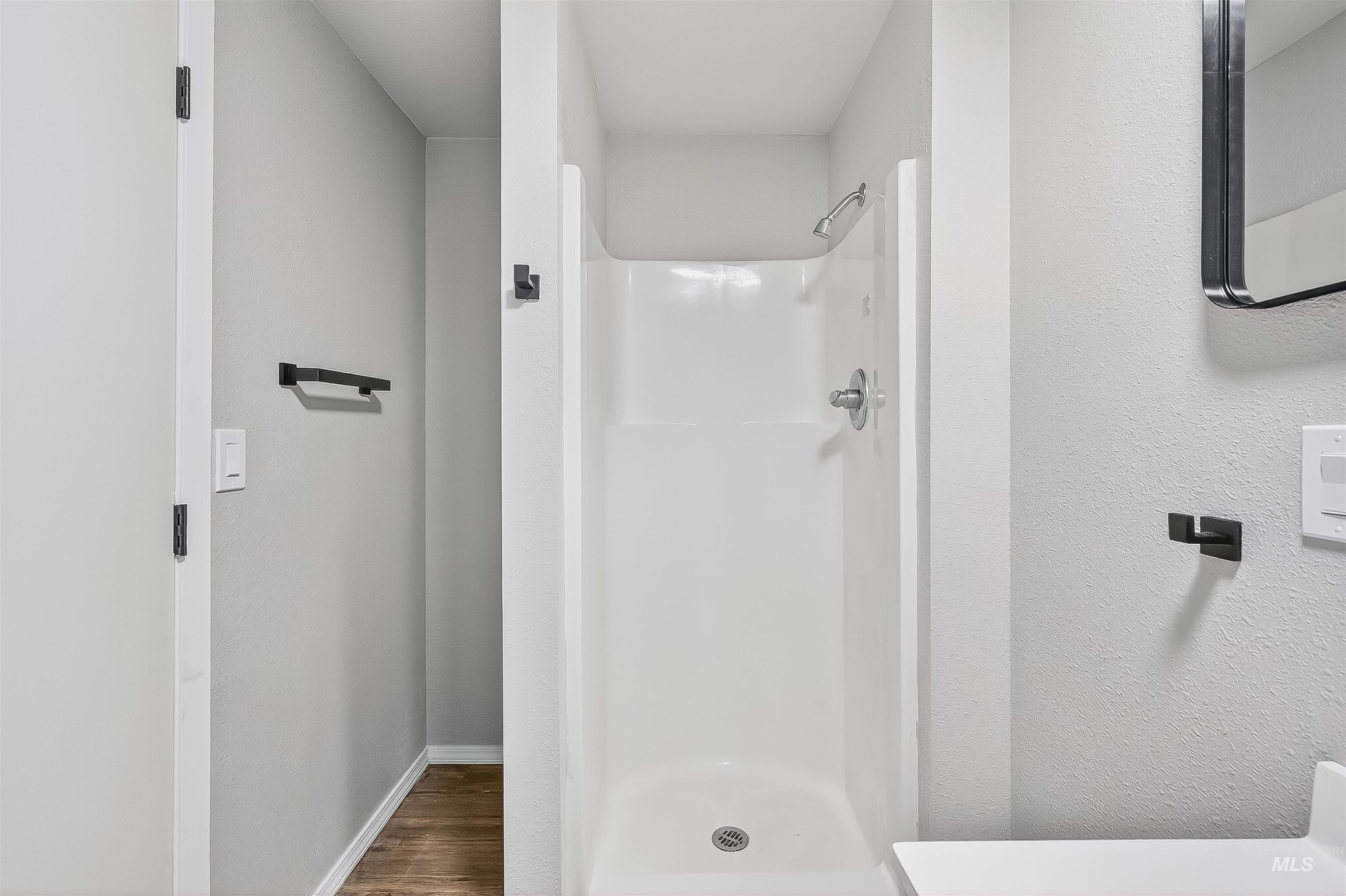 Bathroom with a shower stall and wood finished floors