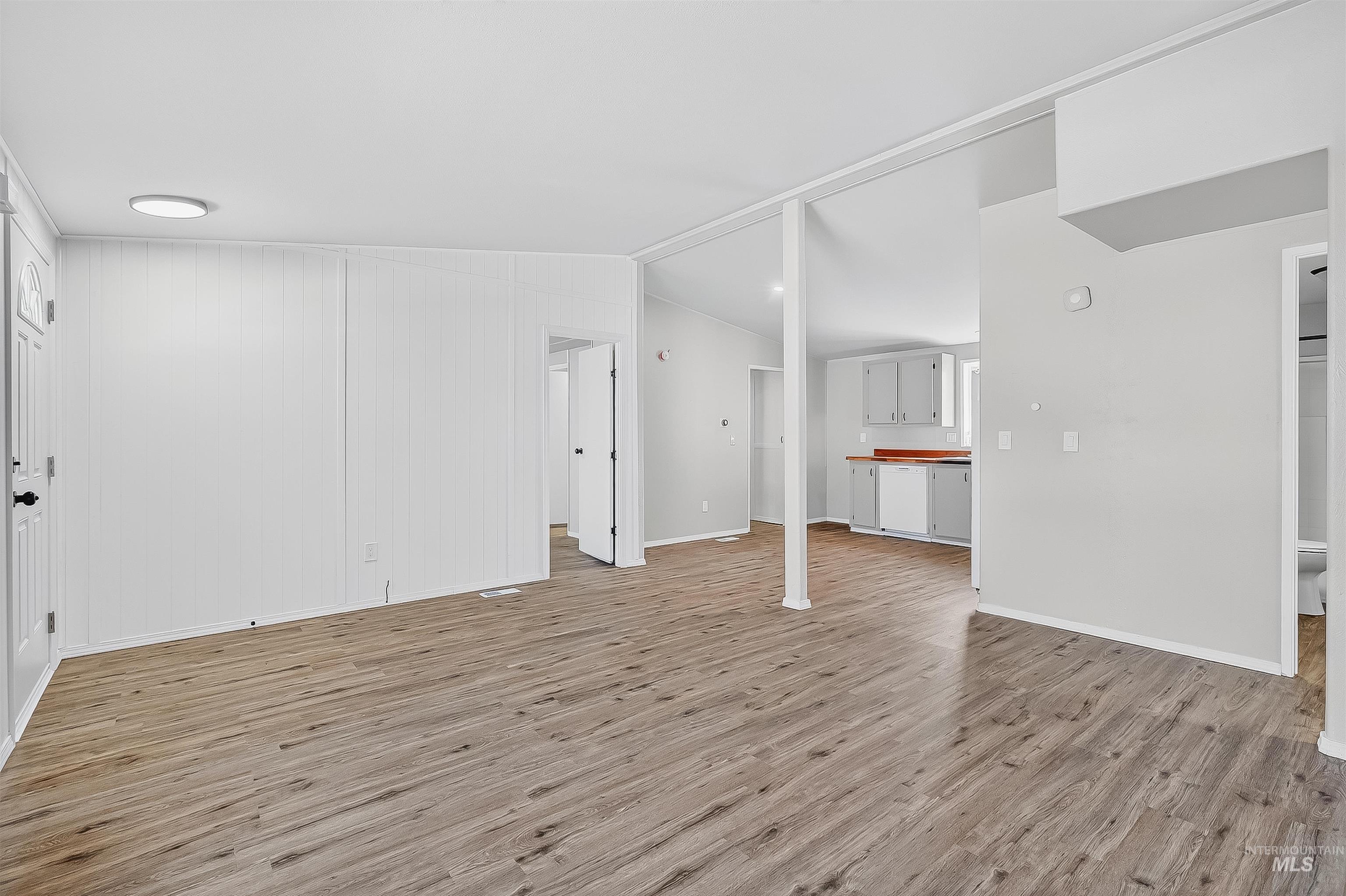 Unfurnished living room with light wood-type flooring and vaulted ceiling