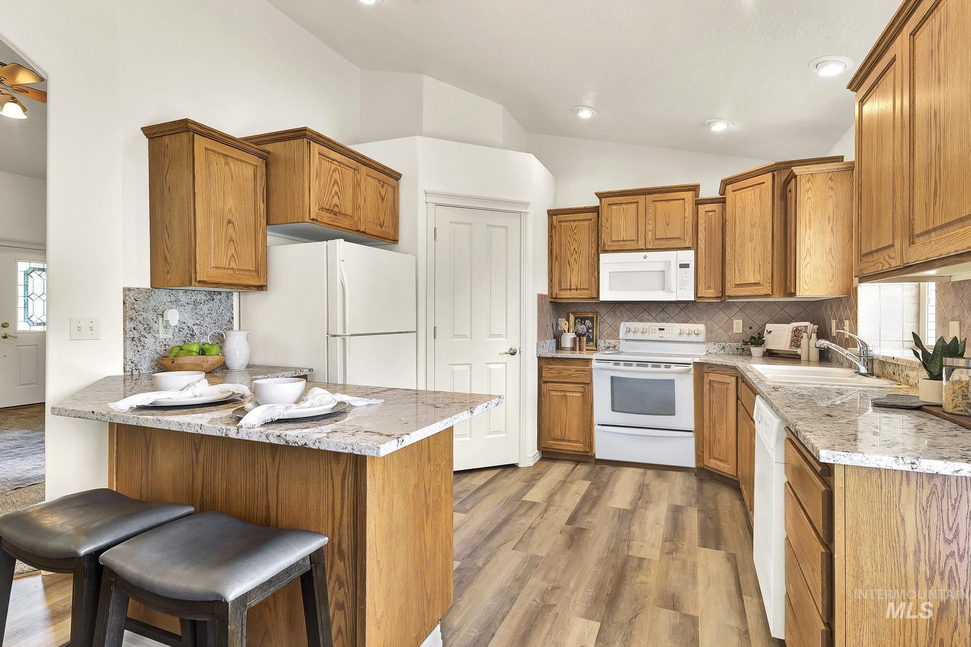 Kitchen with a Flood of natural light! Beautiful newly installed granite countertops, a breakfast bar, bisque appliances, and vaulted ceiling.