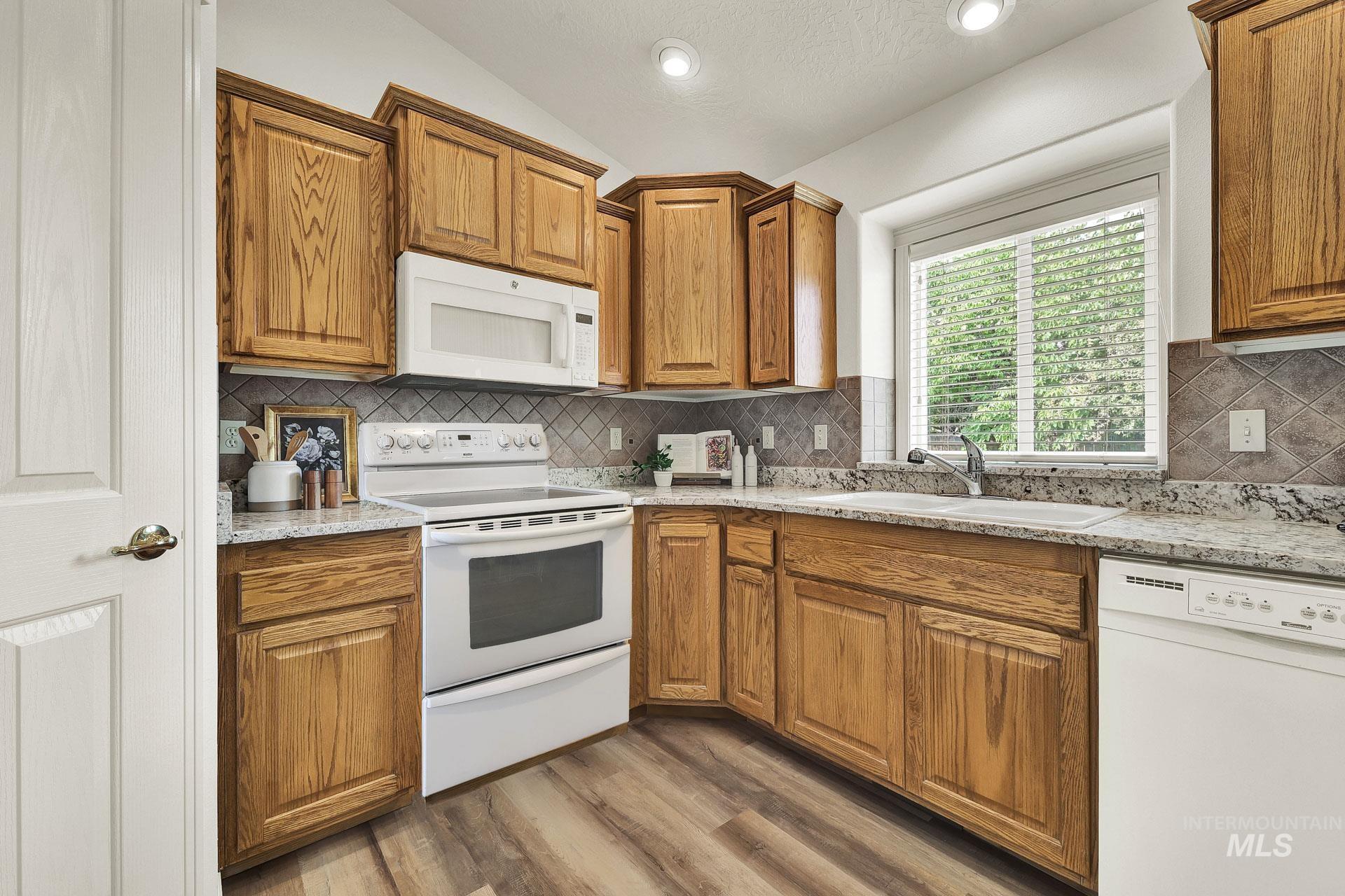 Kitchen with a Flood of natural light! Beautiful newly installed granite countertops, a breakfast bar, bisque appliances, and vaulted ceiling.