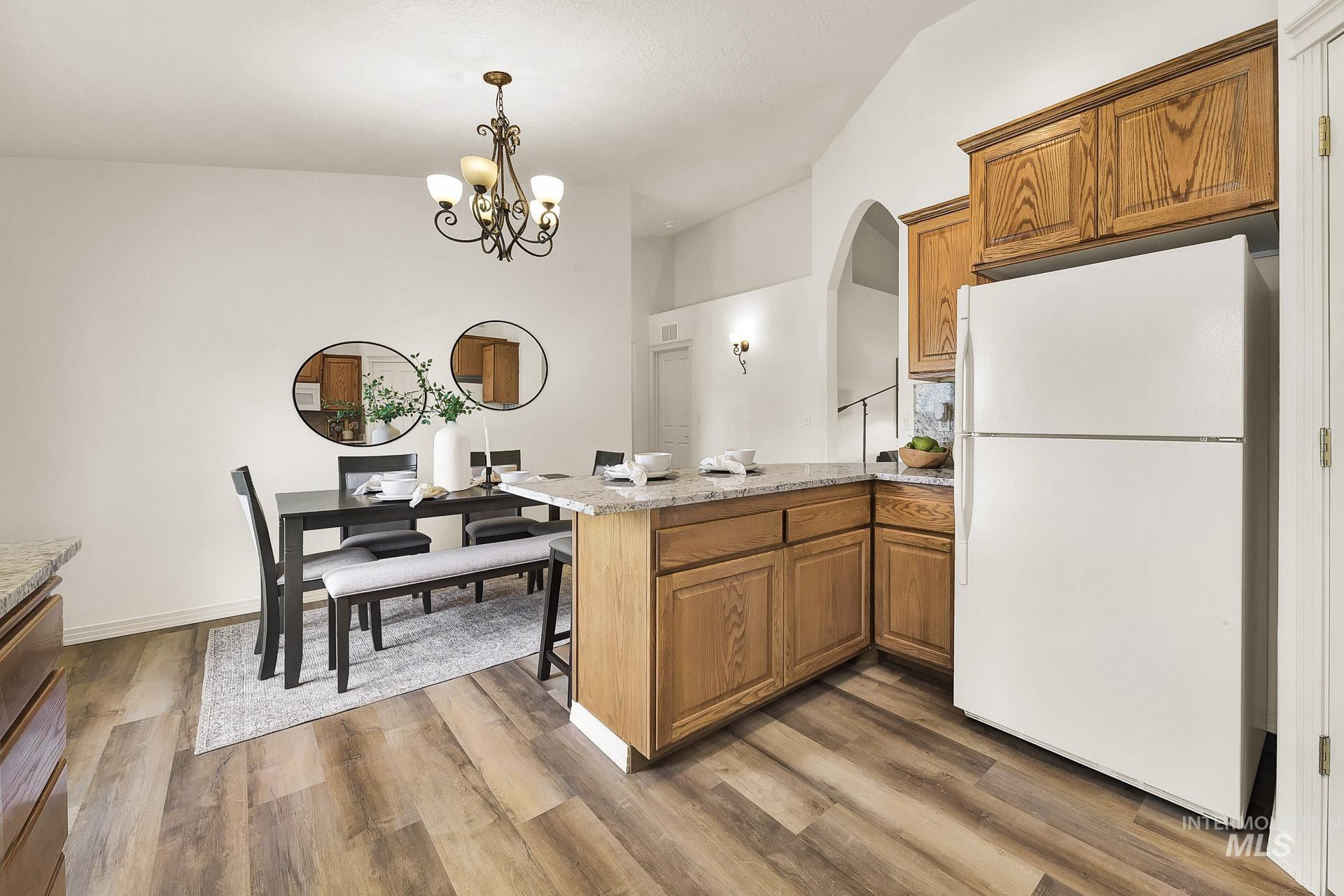 Kitchen featuring freestanding refrigerator, a kitchen bar, and solid wood cabinets, with plenty of natural light  and newly installed LVP flooring with granite countertops