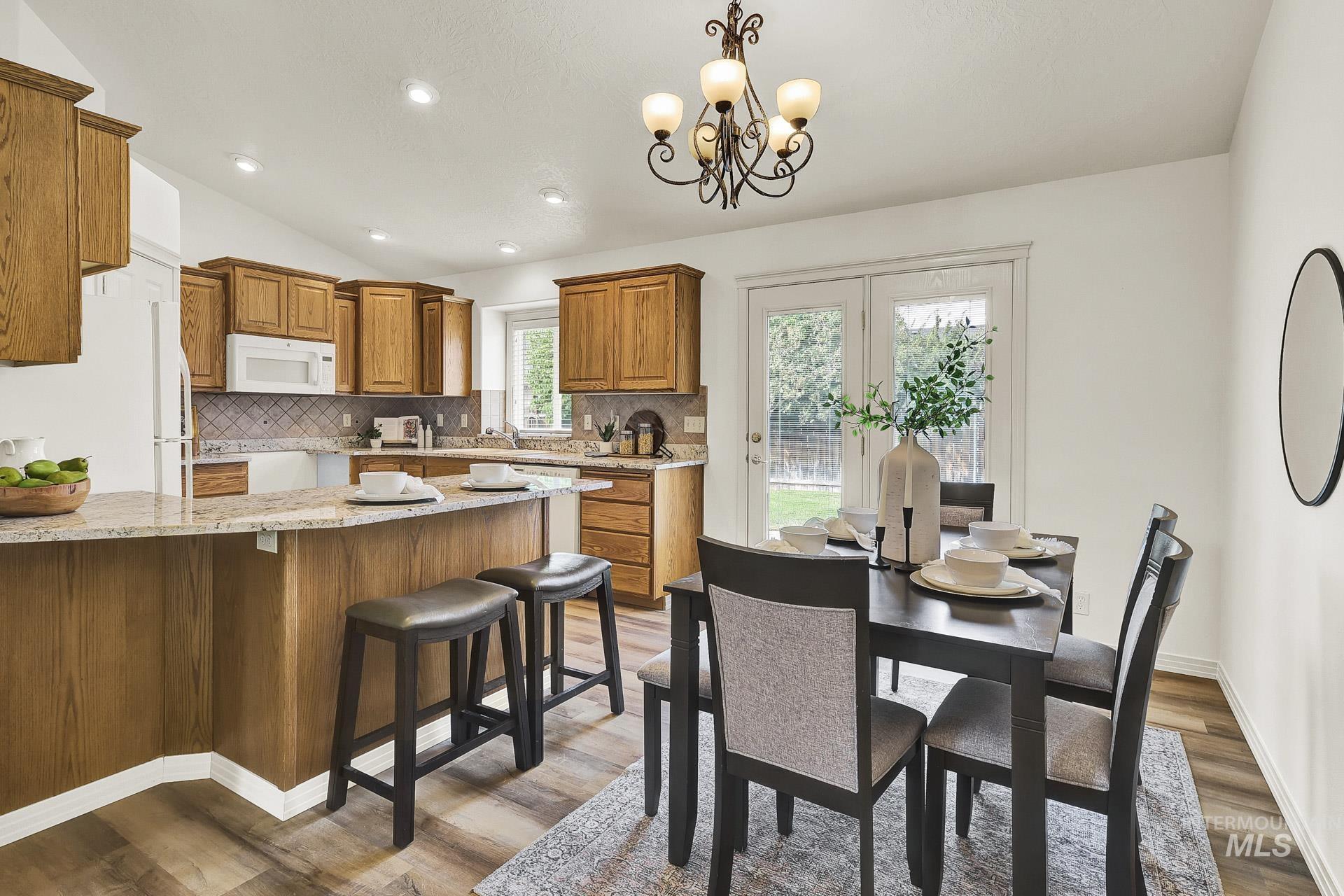 Dining space with vaulted ceiling, and a view a view of the fireplace, recessed lighting, and a sunny patio door with access to the backyard.